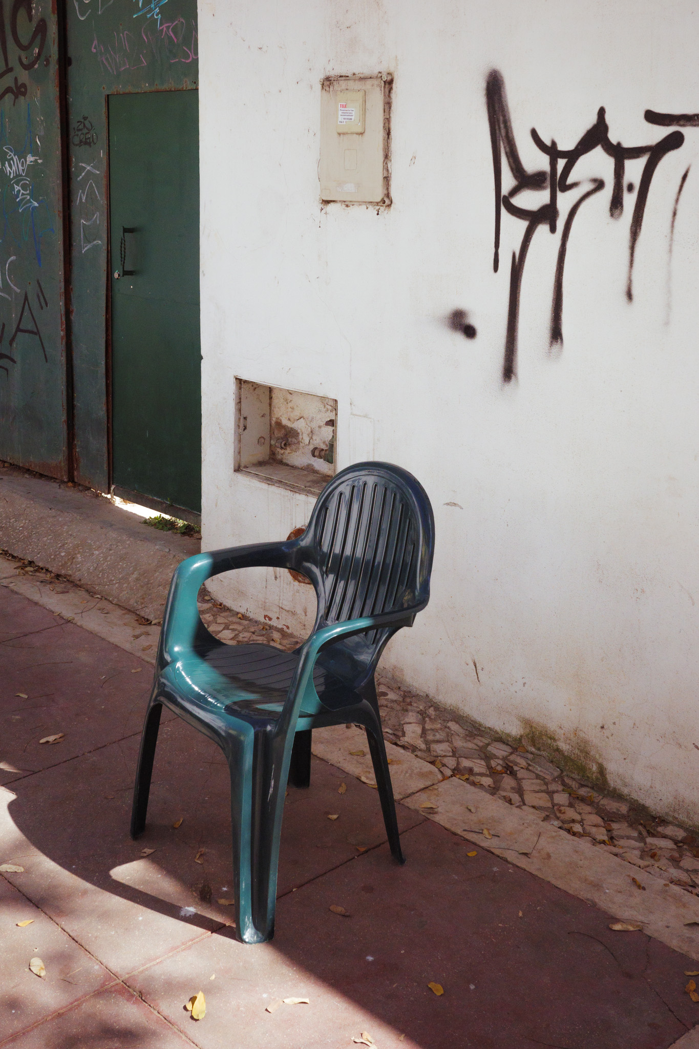 Ein grüner Stuhl in der Mitte einer Straße in Albufeira, Portugal. Von Connor Redmond.