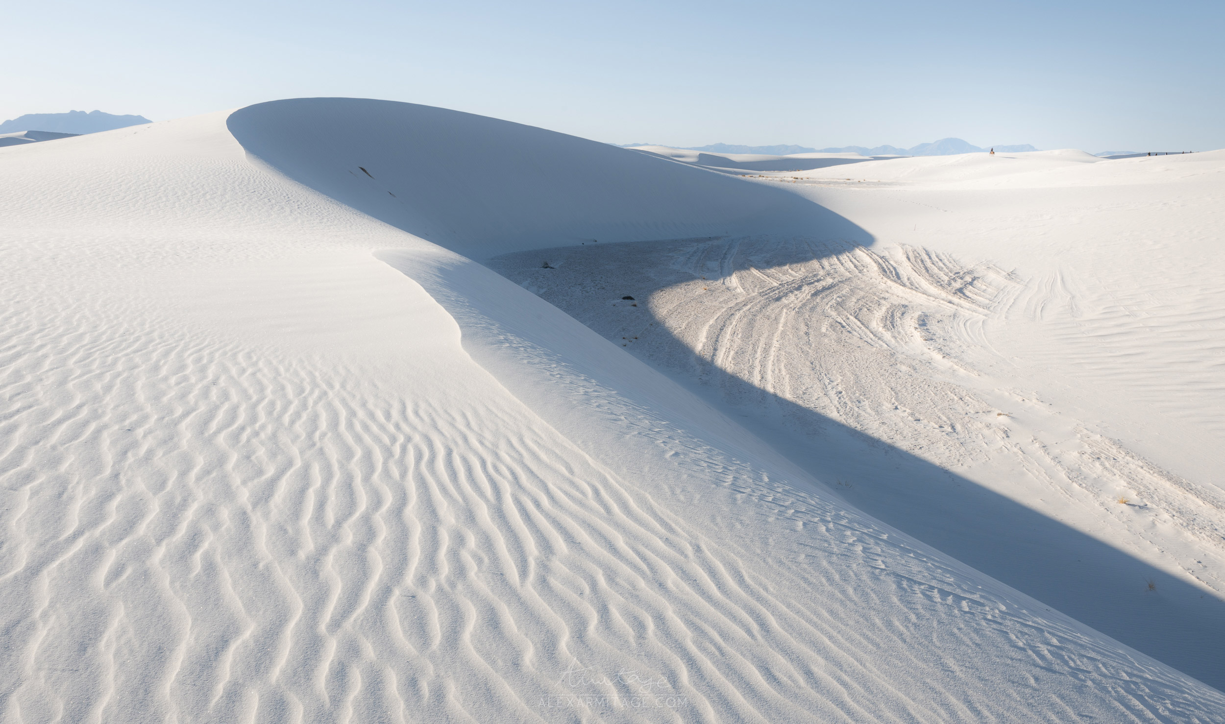 Sloping sand dunes with blue skies in White Sands National Park in New Mexico, USA, taken by landscape photographer Alex Armitage.