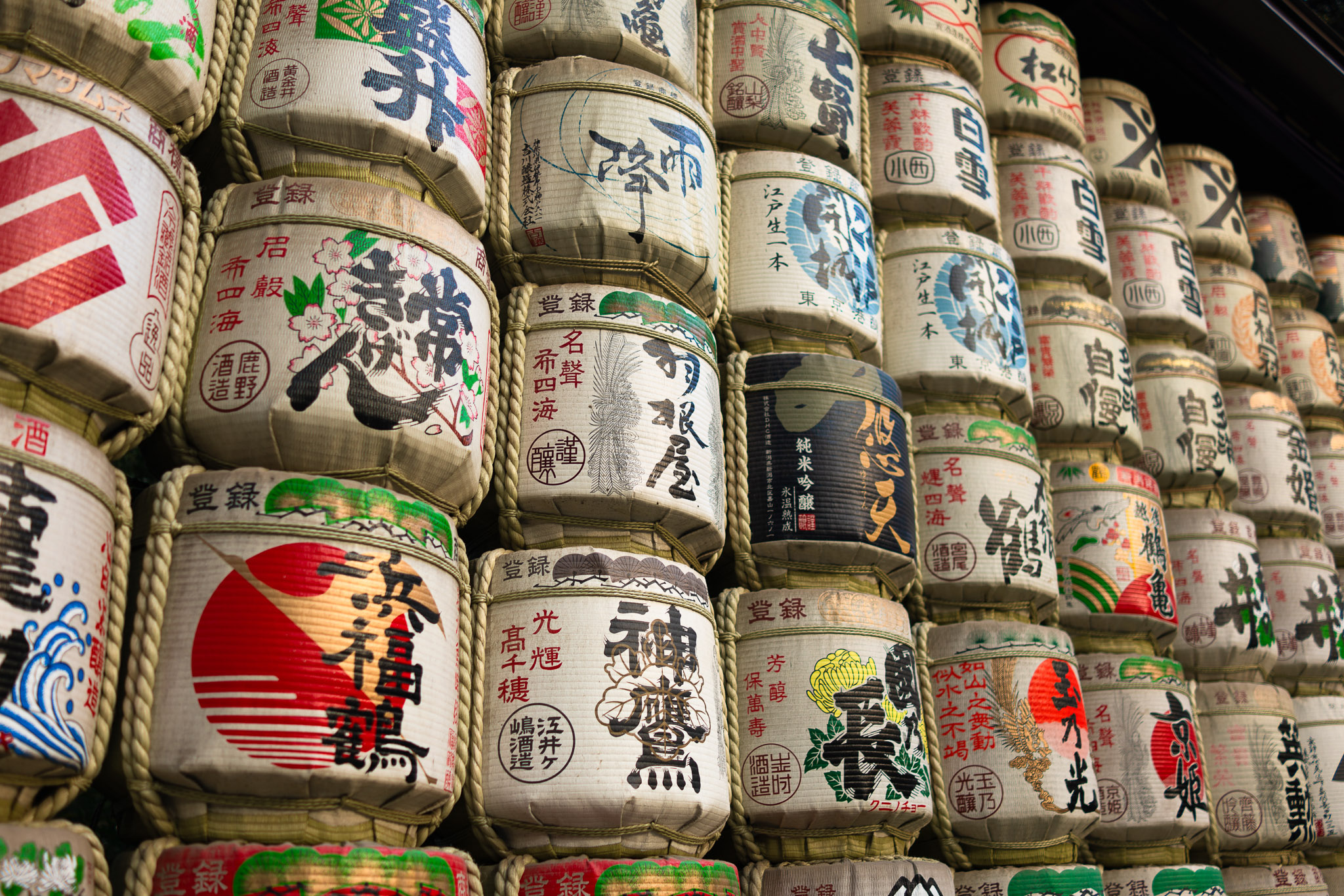 A striking image of stacked Japanese sake barrels, adorned with vibrant traditional artwork, calligraphy, and symbols, representing Japanese culture and craftsmanship. Photographed by Ruby Cruden with a Sony DSC-RX1 RM II.
