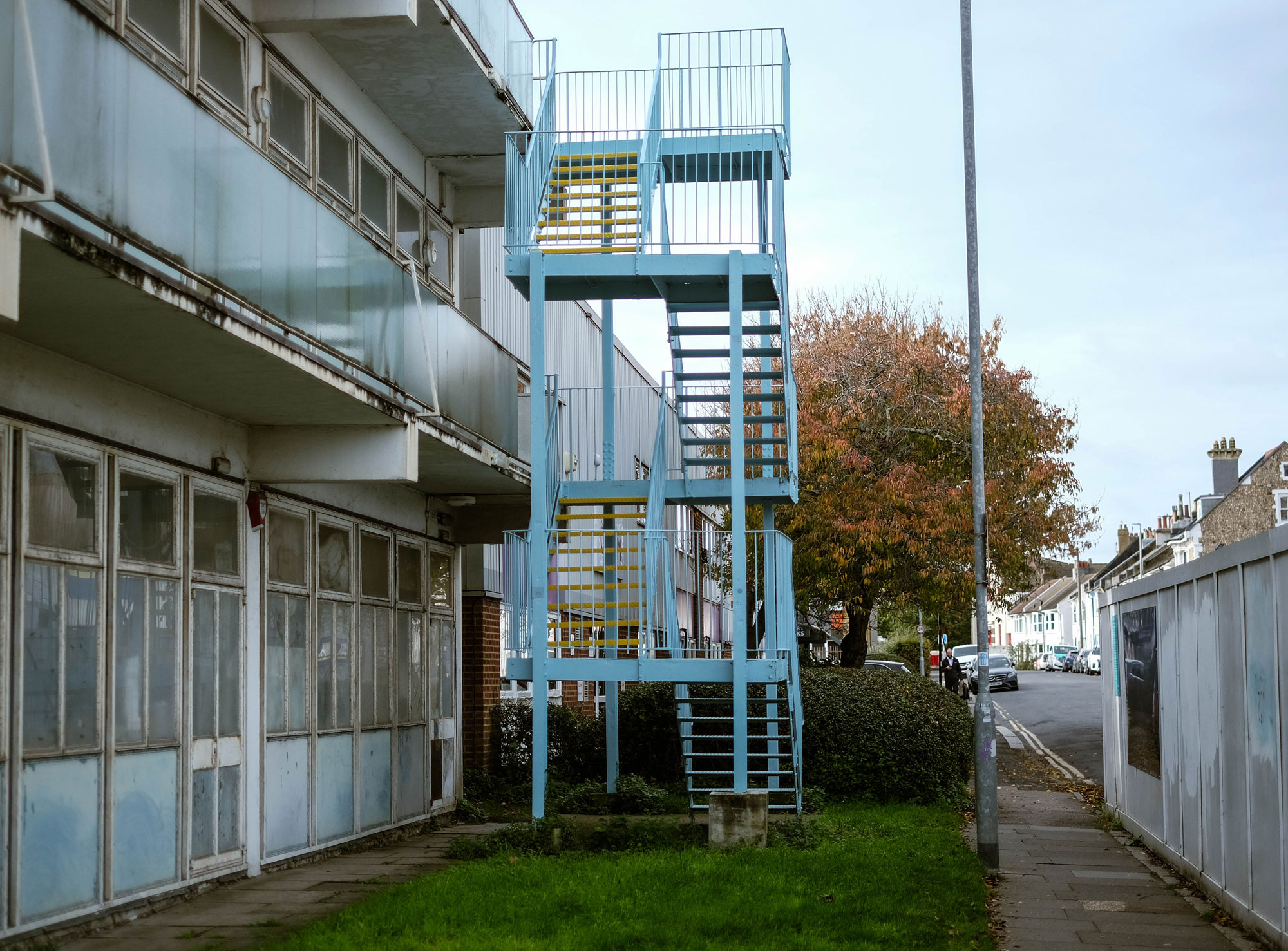 A blue fire escape with yellow steps attached to an older building. Colours have been lightly edited after the shoot.