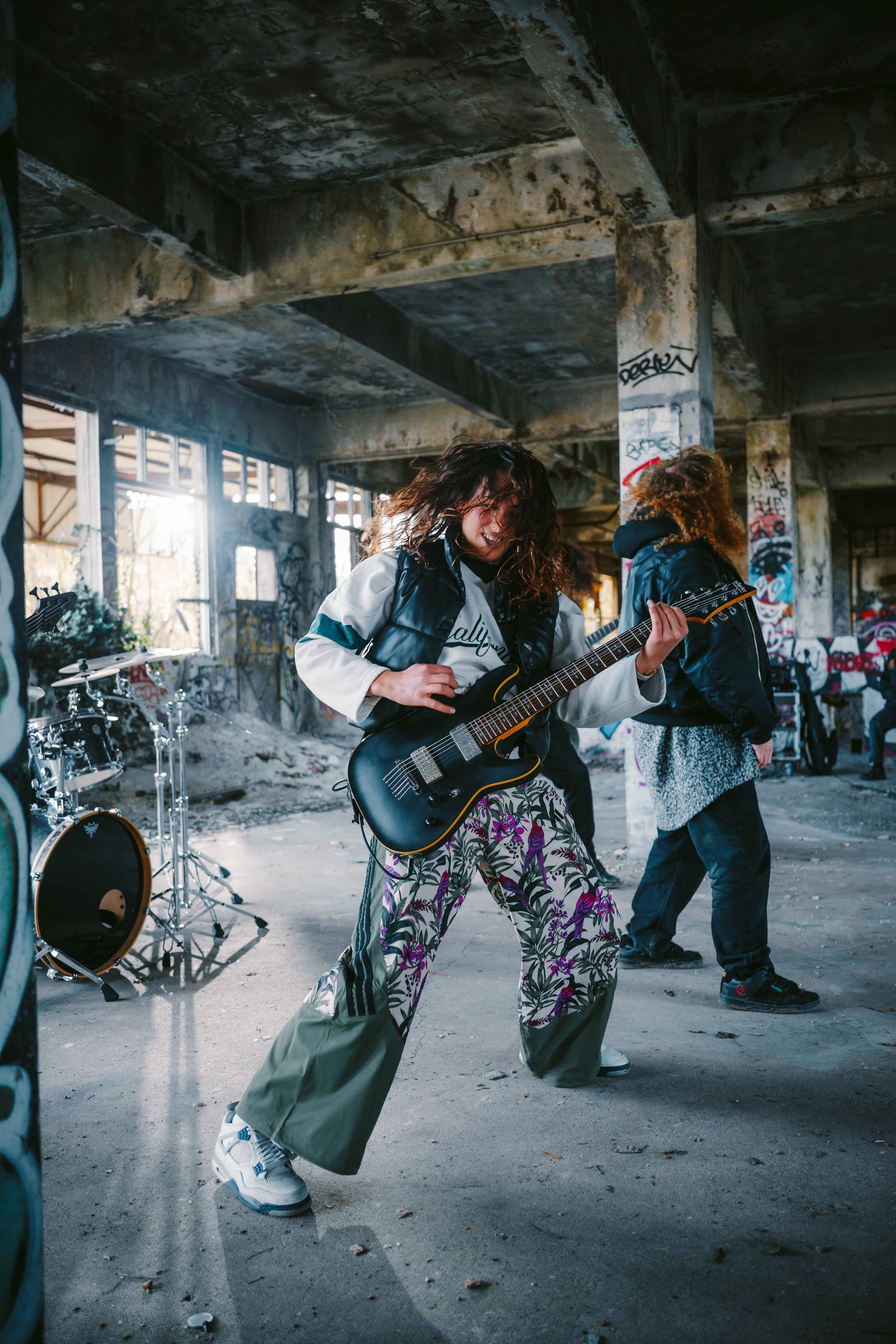Lena Hempel plays electric guitar with her band inside an abandoned, graffiti-covered building during a music video shoot. Photo taken by Lukas Davos.
