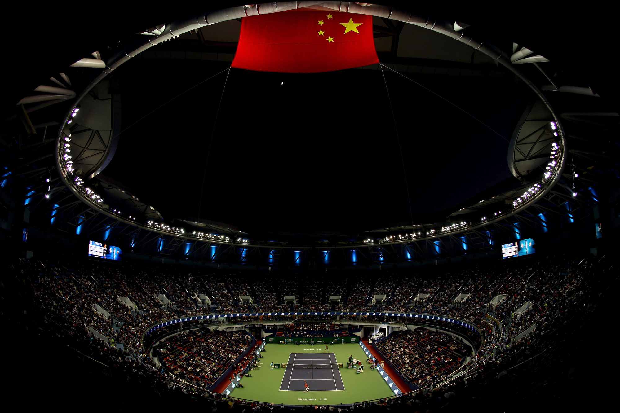 A far away shot of Novak Djokovic of Serbia playing Jo-Wilfried Tsonga of France during the semifinals of the Shanghai Rolex Masters at the Qi Zhong Tennis Centre in Shanghai, China. The entire stadium is shot by a wide-angle lens, with the night sky above.
