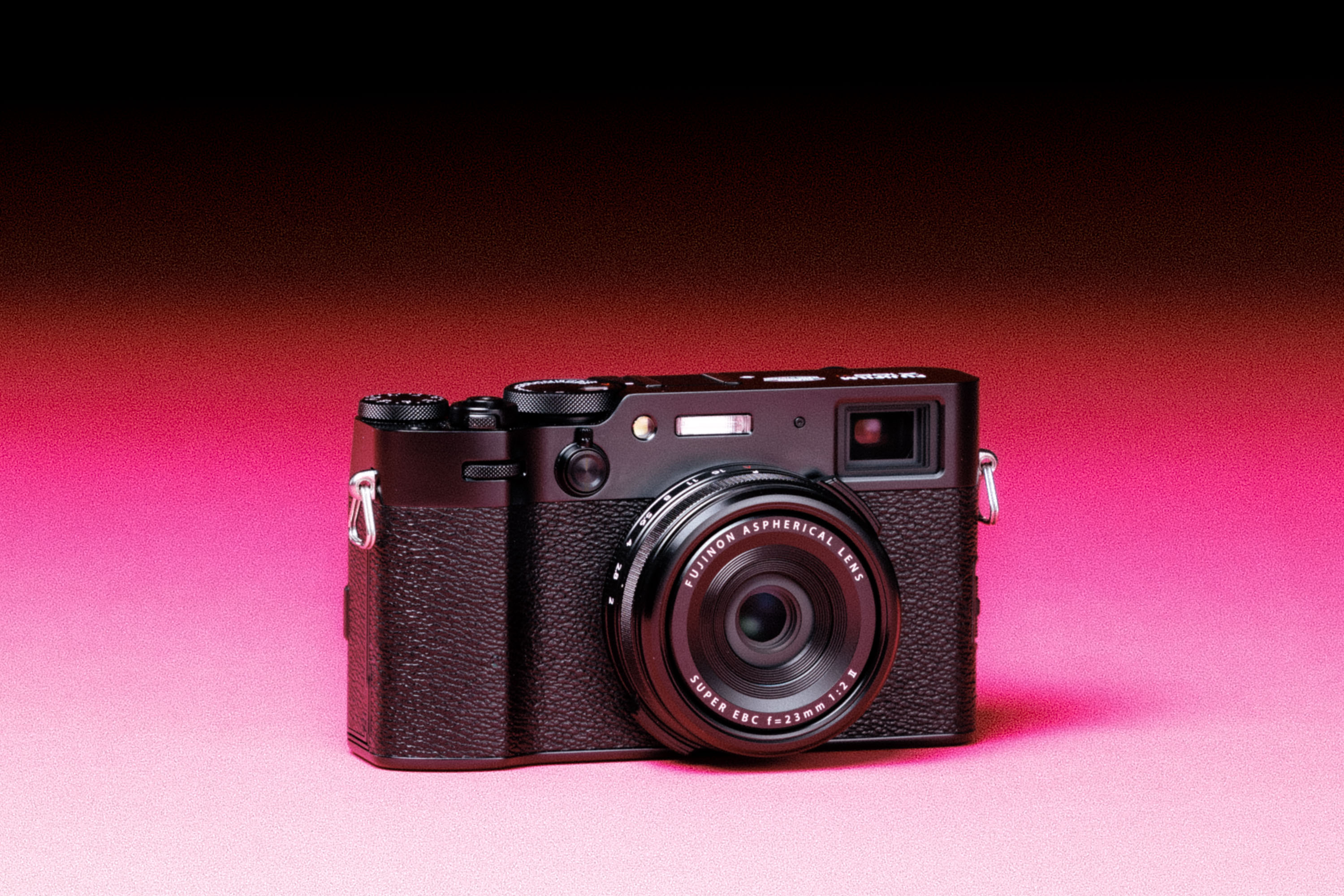  A used Fujifilm X100VI with an added film-like grain effect on a graduated pink background.
