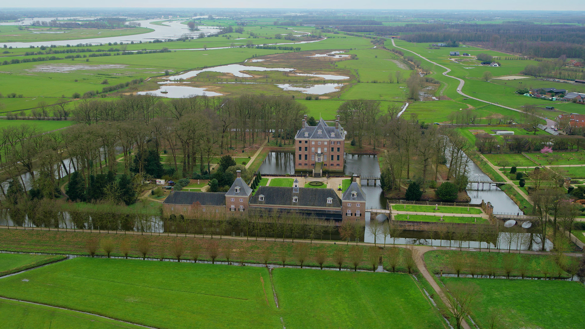 Ontdek de schoonheid van een historisch kasteel, gelegen in een groen landschap met grachten, tuinen en kronkelende rivieren, vastgelegd vanuit een indrukwekkend luchtperspectief, gemaakt met de DJI Inspire 3