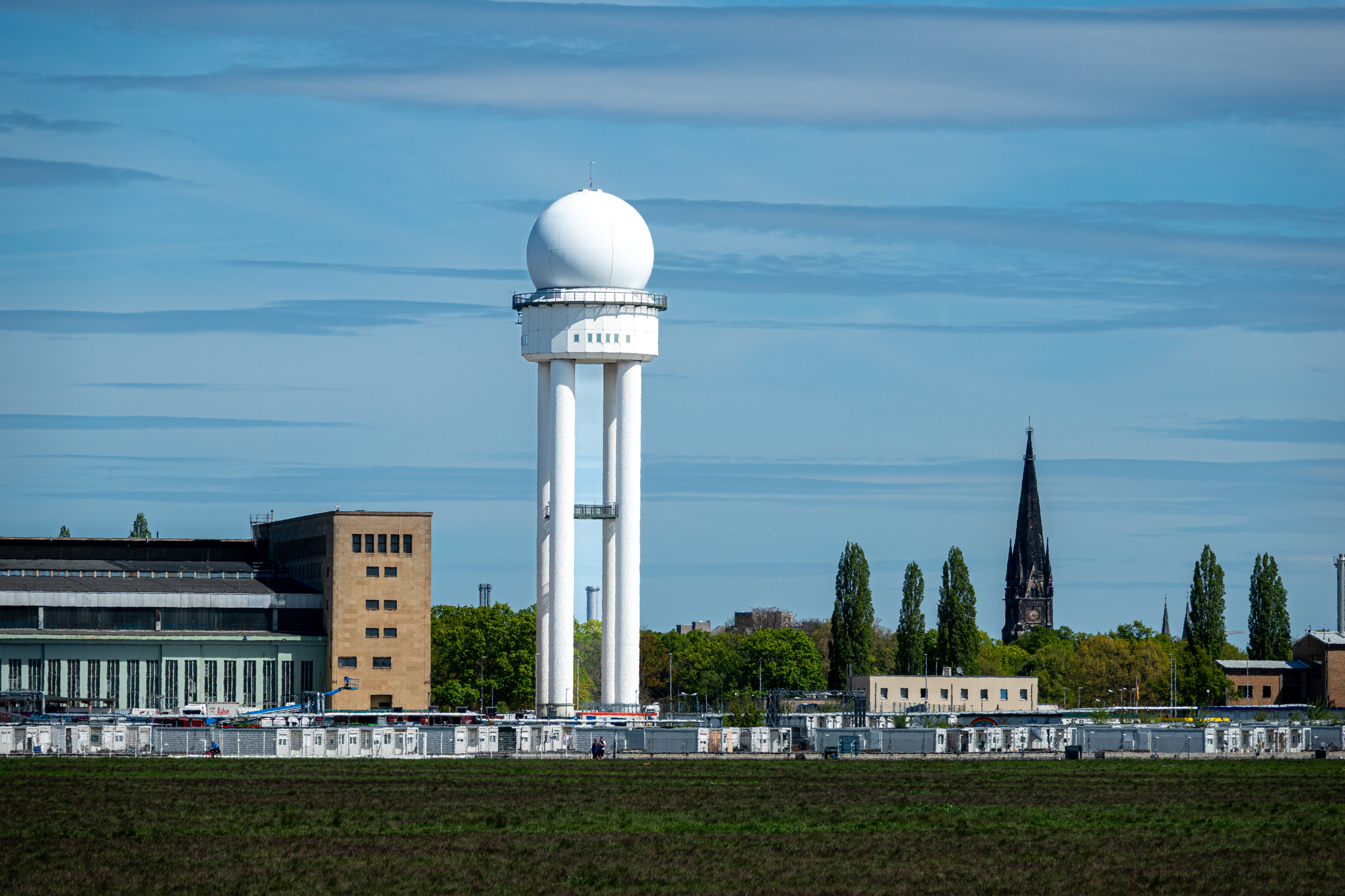 A white radar tower stands out against the cityscape under a clear sky.