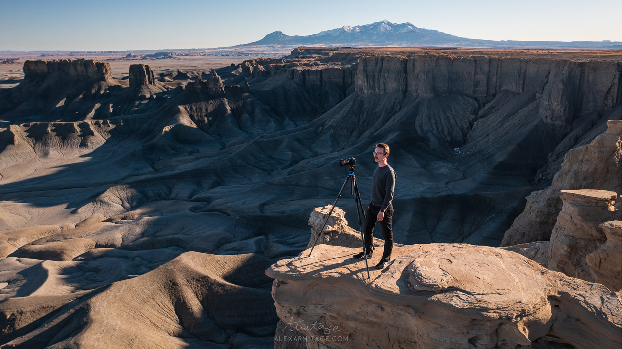 A person standing with a camera setup over a canyon.