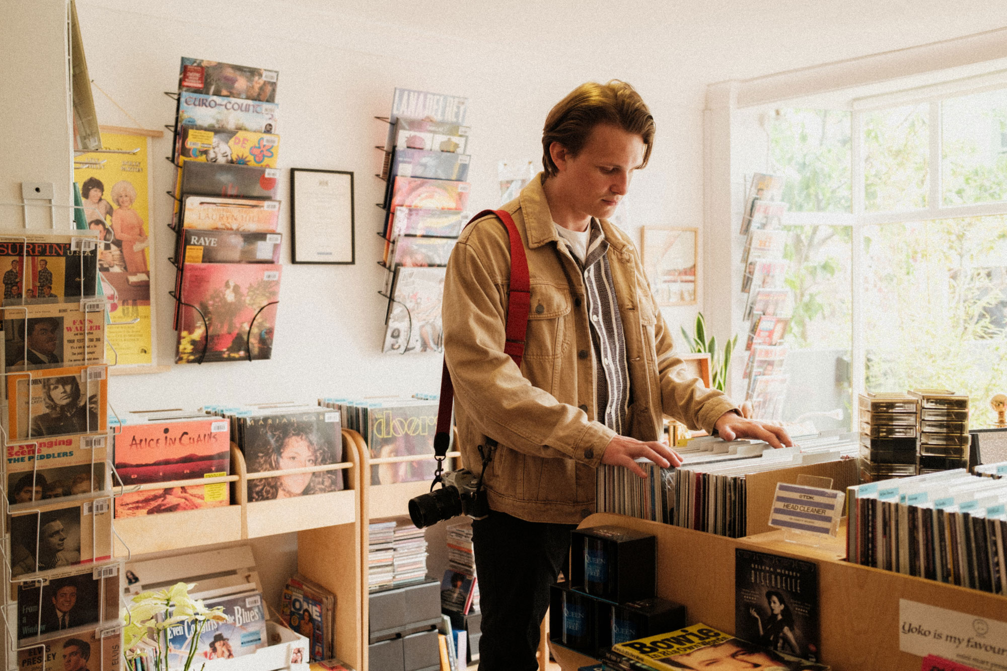 A person with a camera over their shoulder browses vinyl records in Dream Street Records shop, in Brighton, England