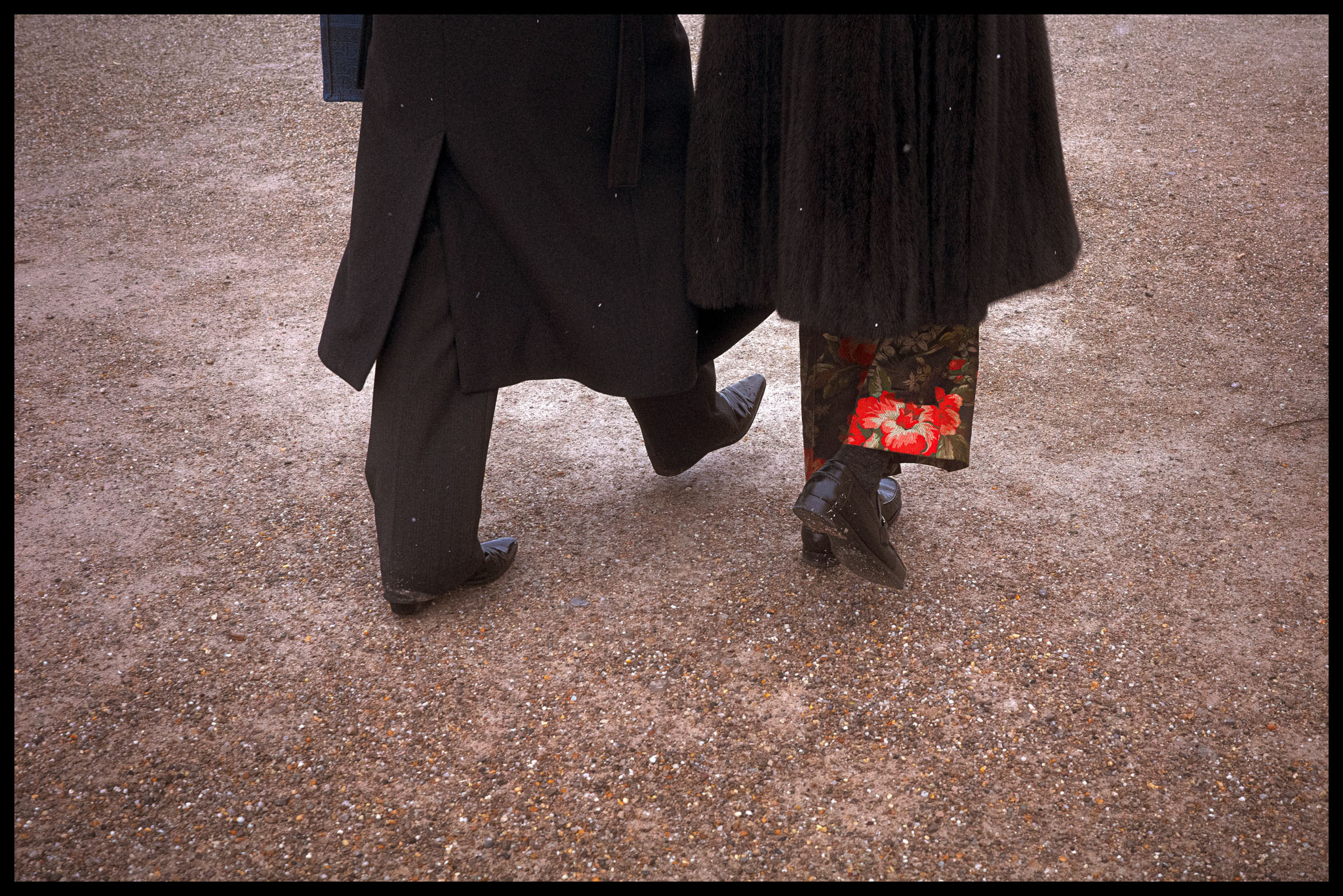 Two people in graduation gowns walking. All we can see is the shoes and trousers by Adam Hince.