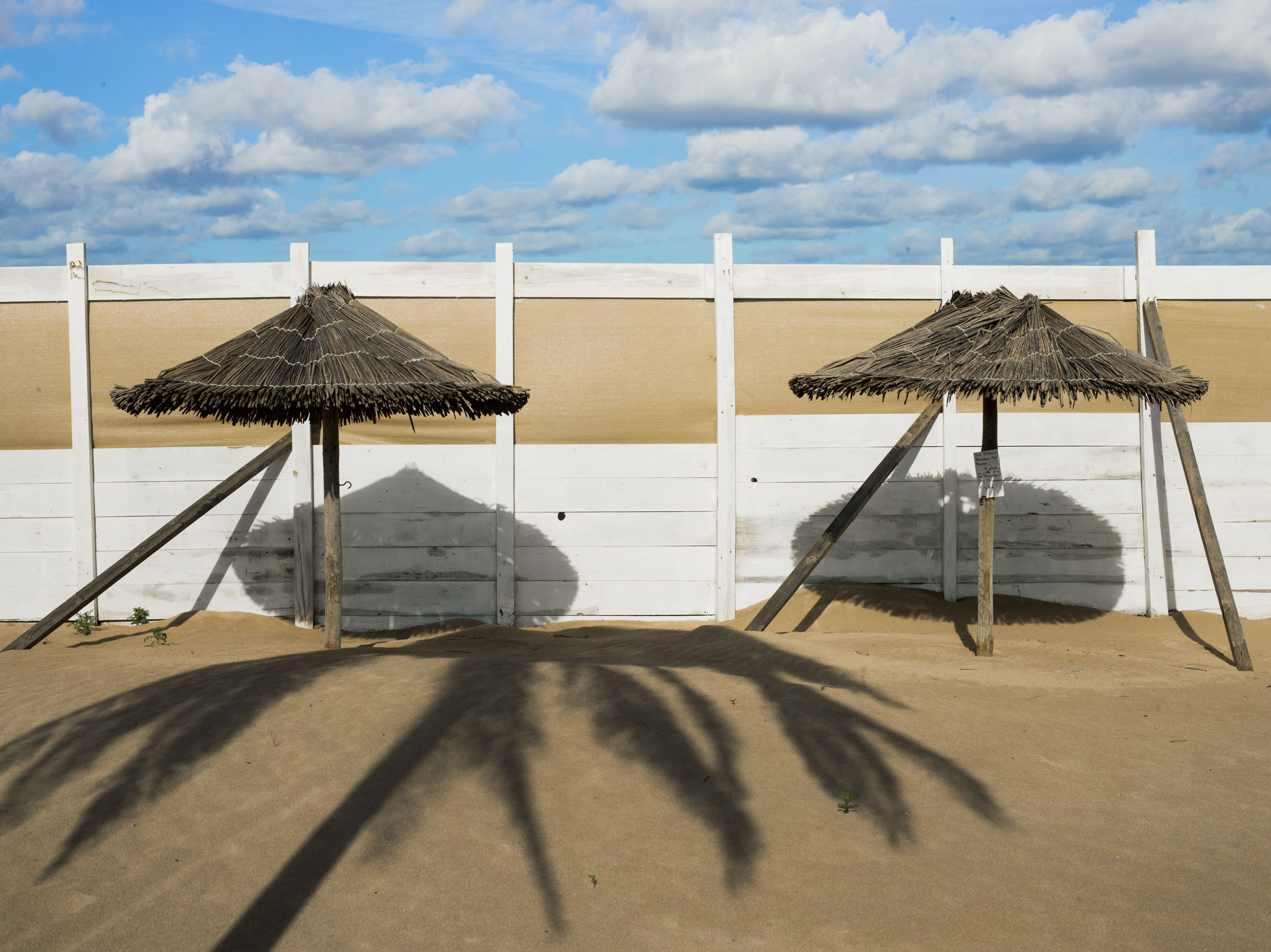 A photo of two parasols under the morning sun casting a shadow, shot on Phase One P45 Plus by Ian Howorth