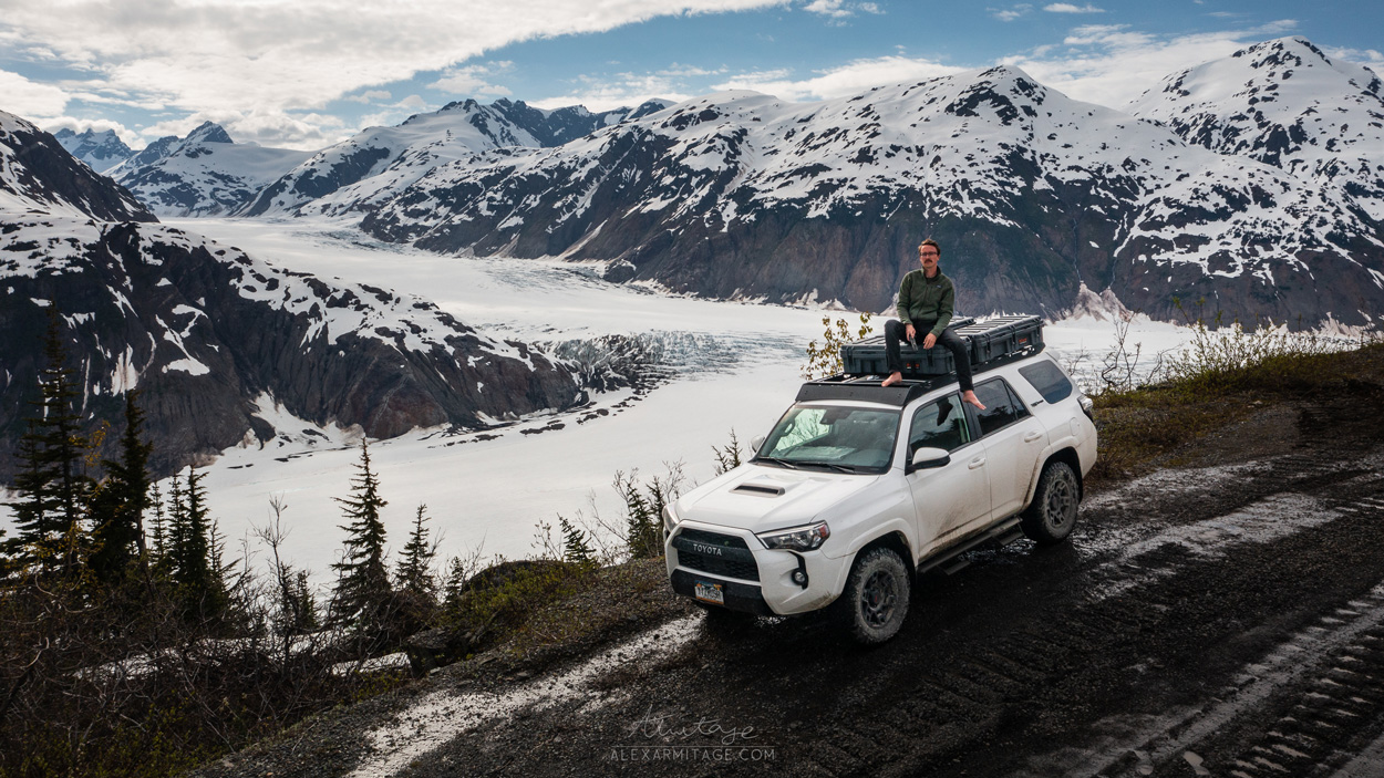 A person sits on a vehicle by the mountains.