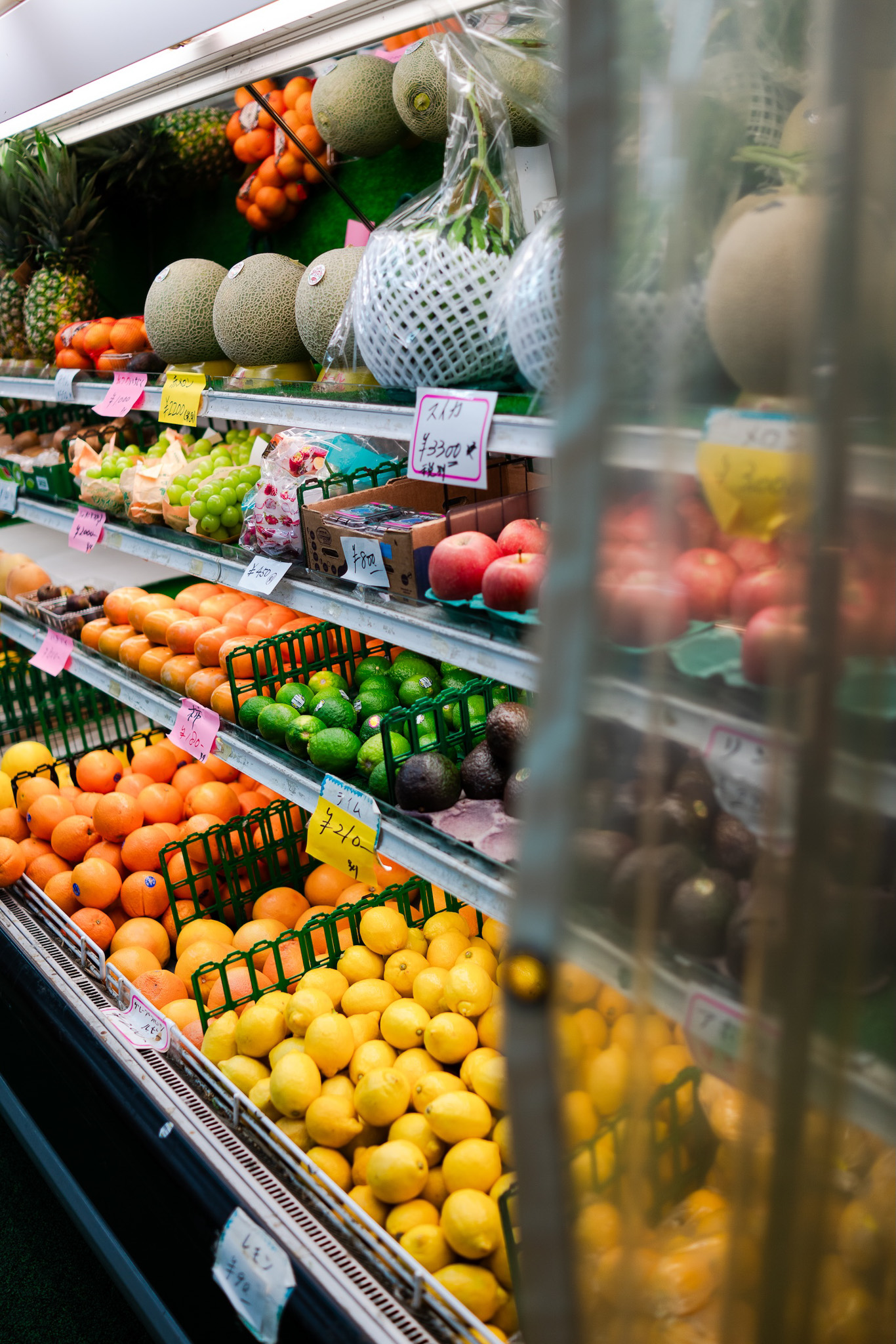 An eye-catching display of fresh fruits in a Japanese market, featuring melons, oranges, lemons, and more, arranged neatly with colourful price tags showcasing local produce. Photographed by Ruby Cruden with a Sony DSC-RX1 RM II.