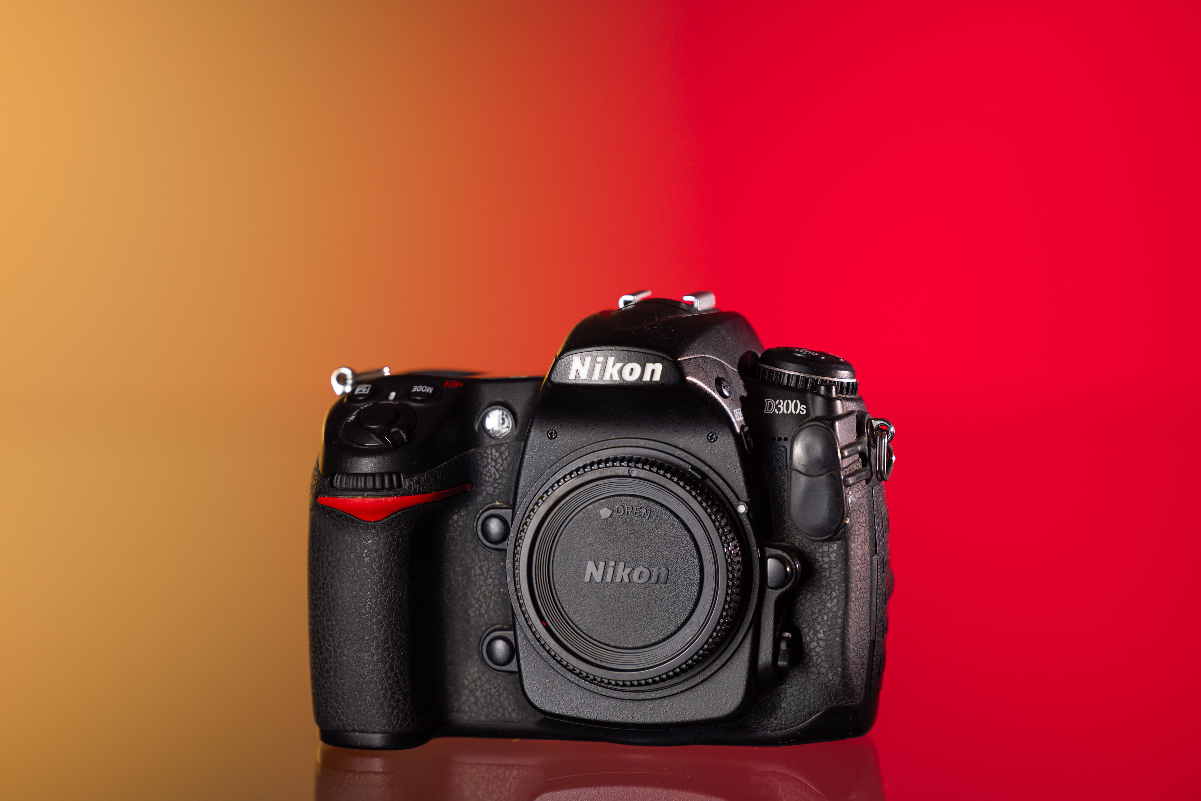 Cámara Nikon D300S de segunda mano sobre un fondo amarillo y rojo