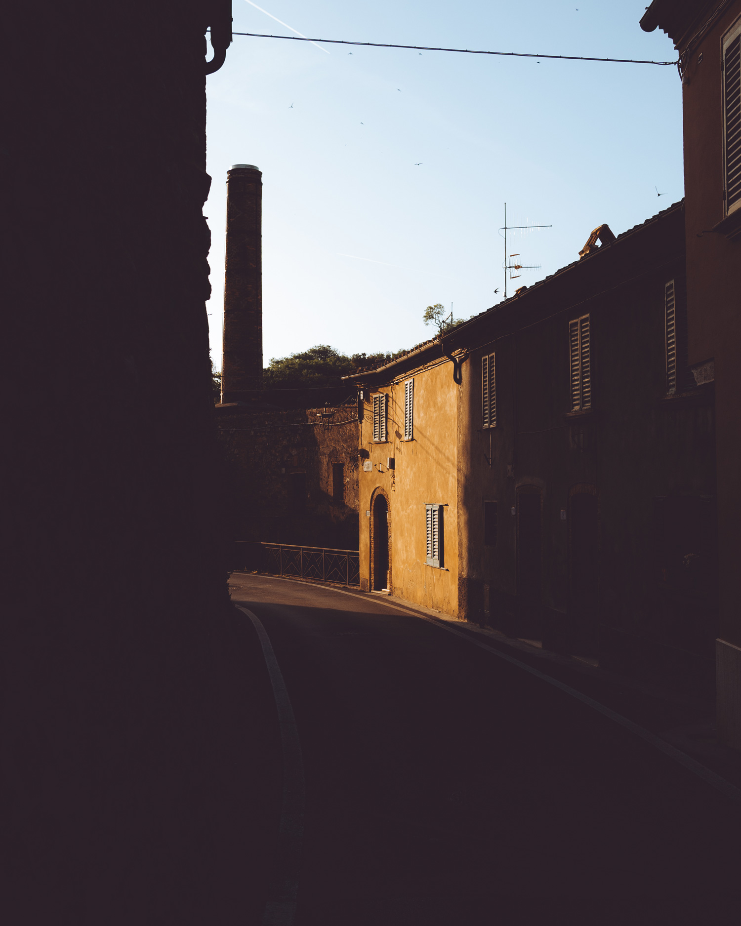 A street in Petrolo, Tuscany. One house is illuminated by sunlight, the rest of the street is covered by shadow.