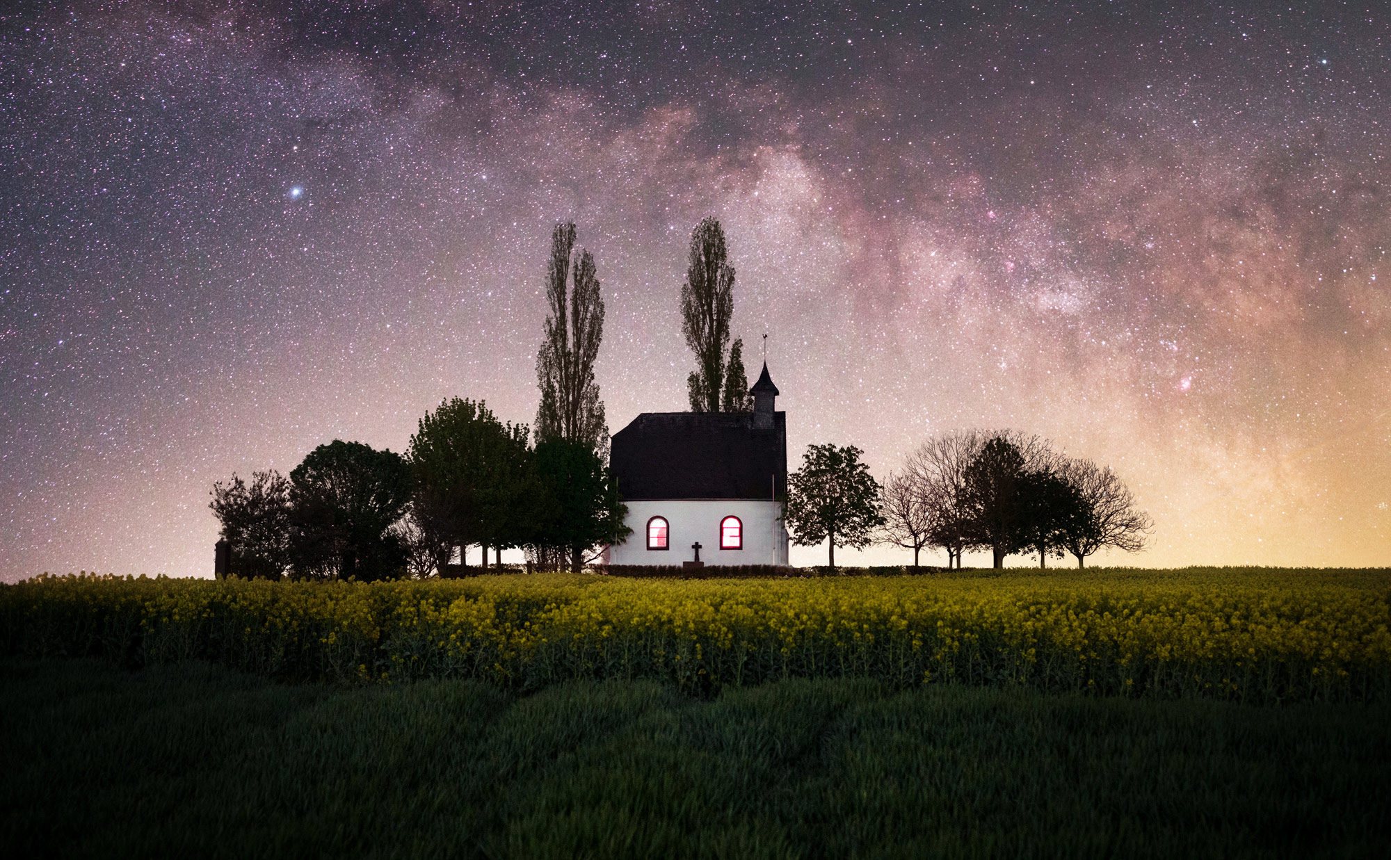 A starry sky picture of a house on top of a hill
