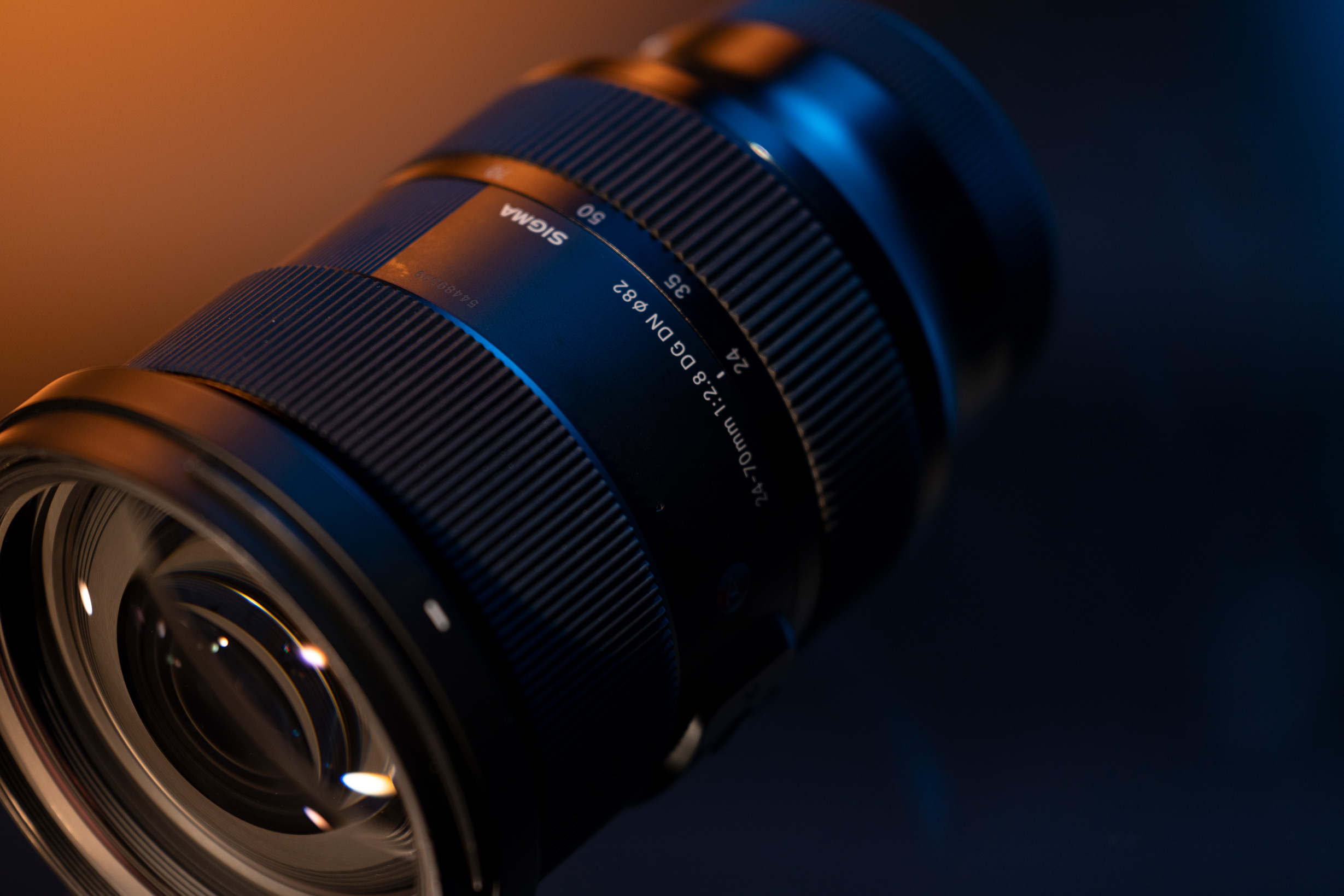 Sigma 24-70mm f/2.8 DG DN ART op een oranje en zwarte achtergrond