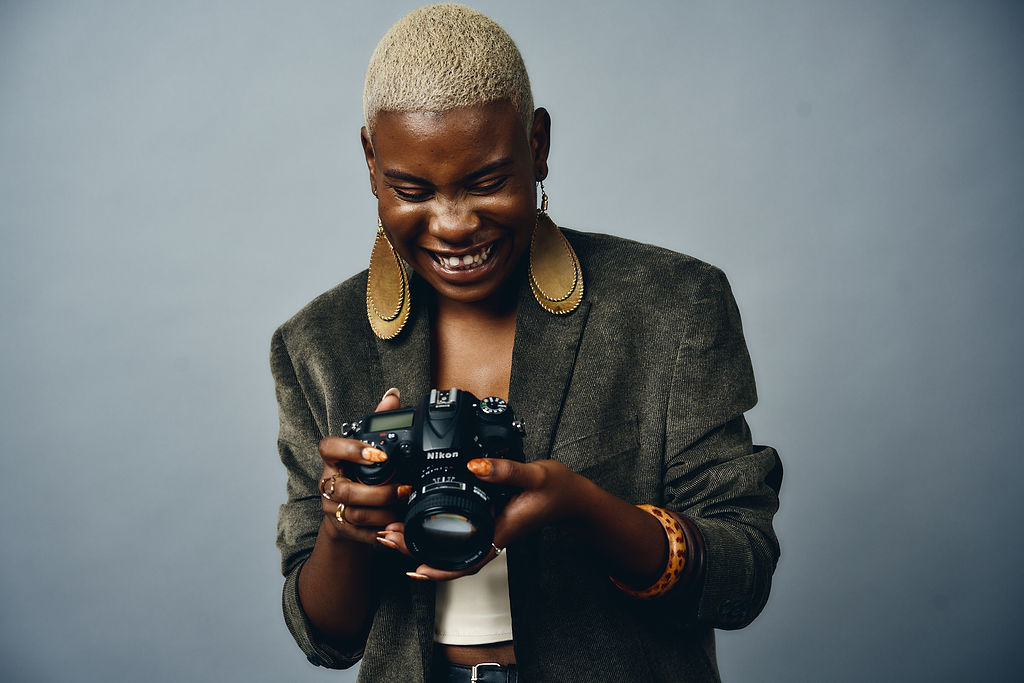 A photographer smiling as they look down at the camera in their hands