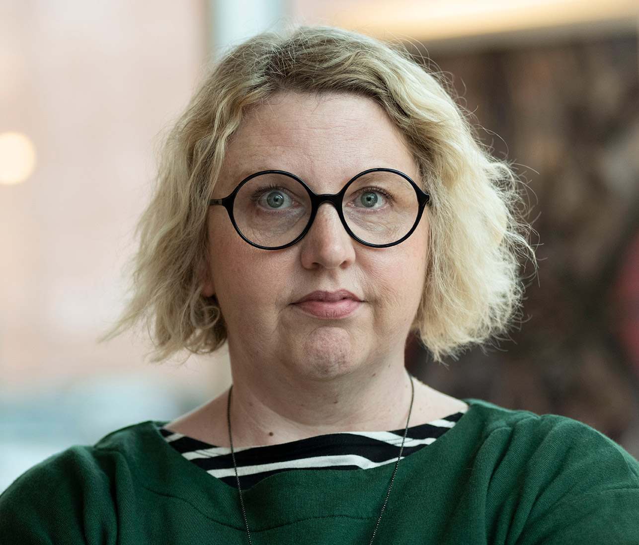 A portrait photo of Haley Morris-Caferio wearing glasses and a green top