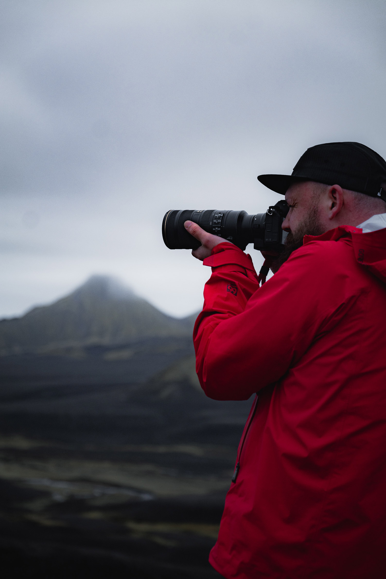 Paul Watson wearing a red anorak shooting with the Nikon Z6 in Iceland, with mountains and clouds in the background.