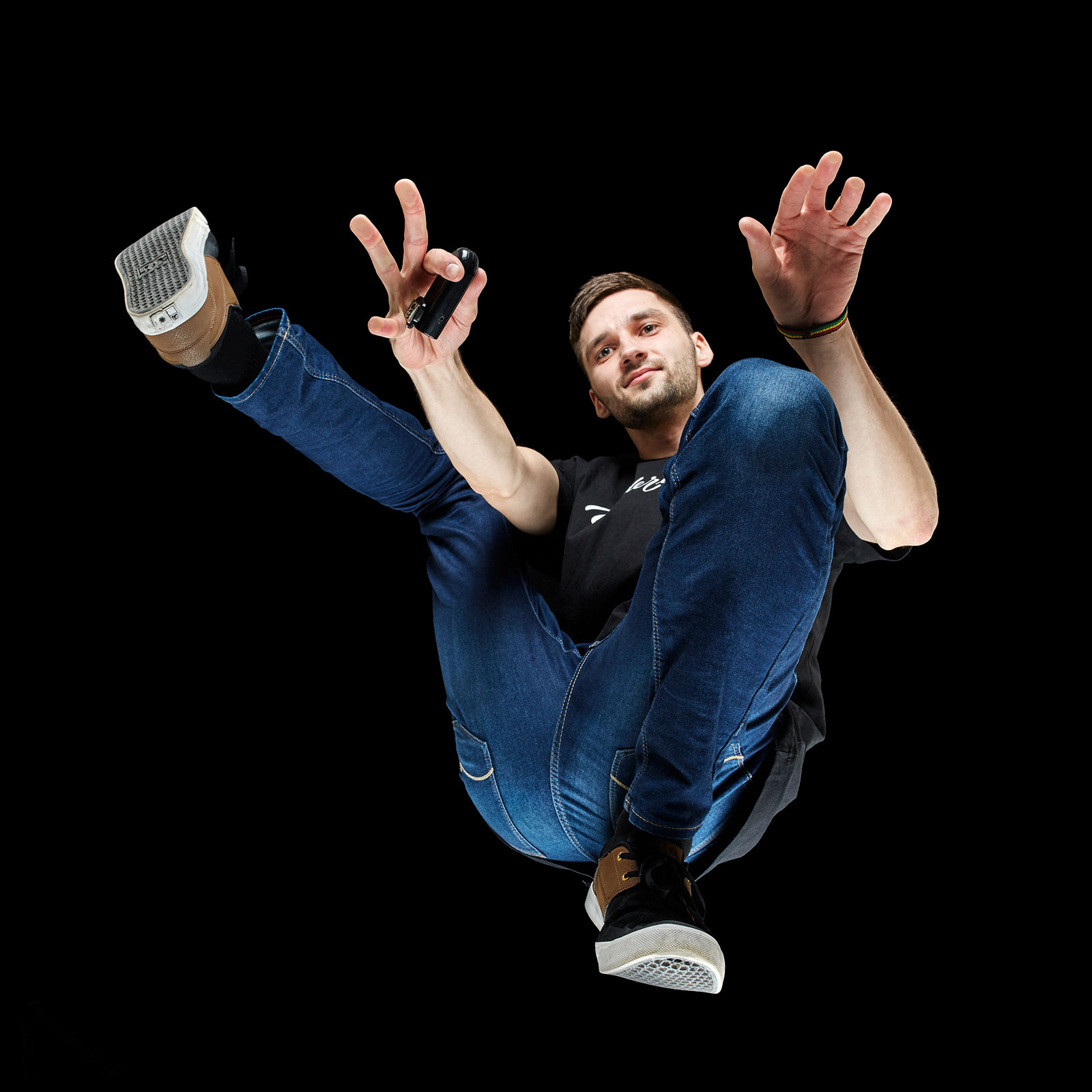 Fotograf Andrius Burba, in blauen Jeans, aufgenommen von unten vor einem schwarzen Hintergrund