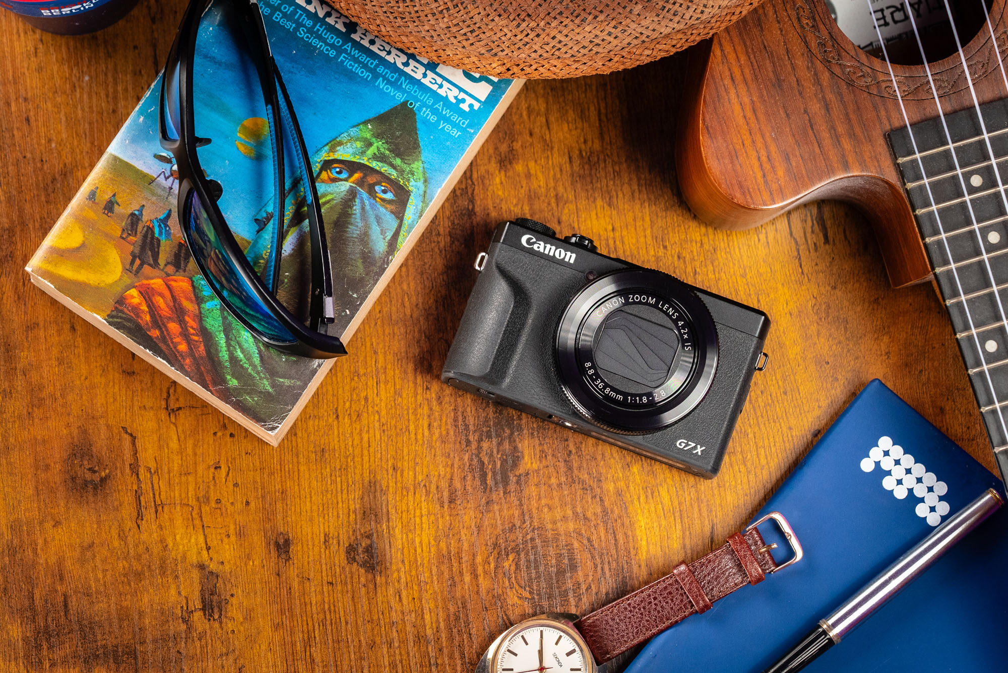 A flatlay style image of the Canon G7 X III with various travel items around it. 