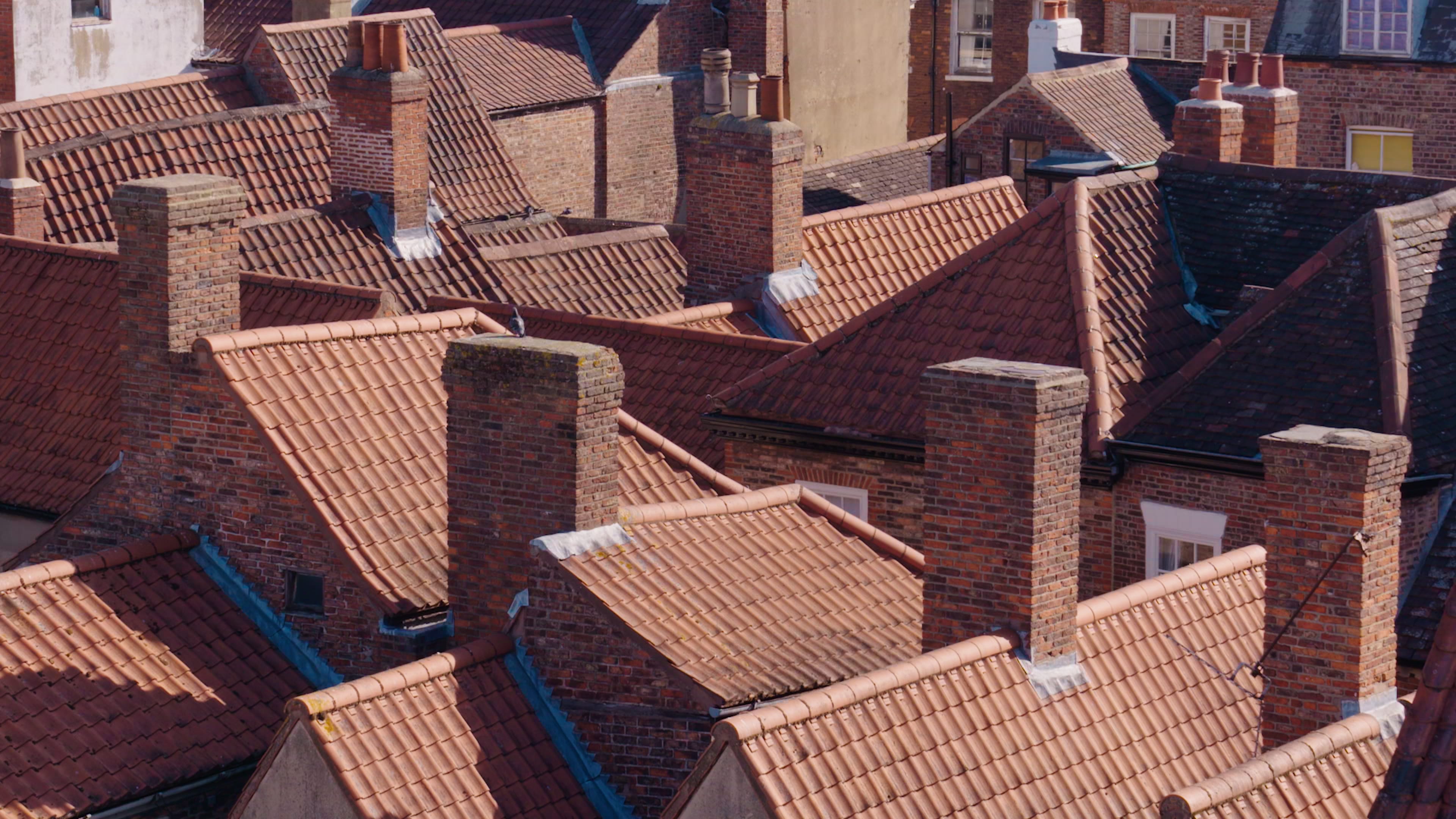 A still of a series of traditional tiled roofs and red-brick chimneys in York, taken as part of an establishing shot