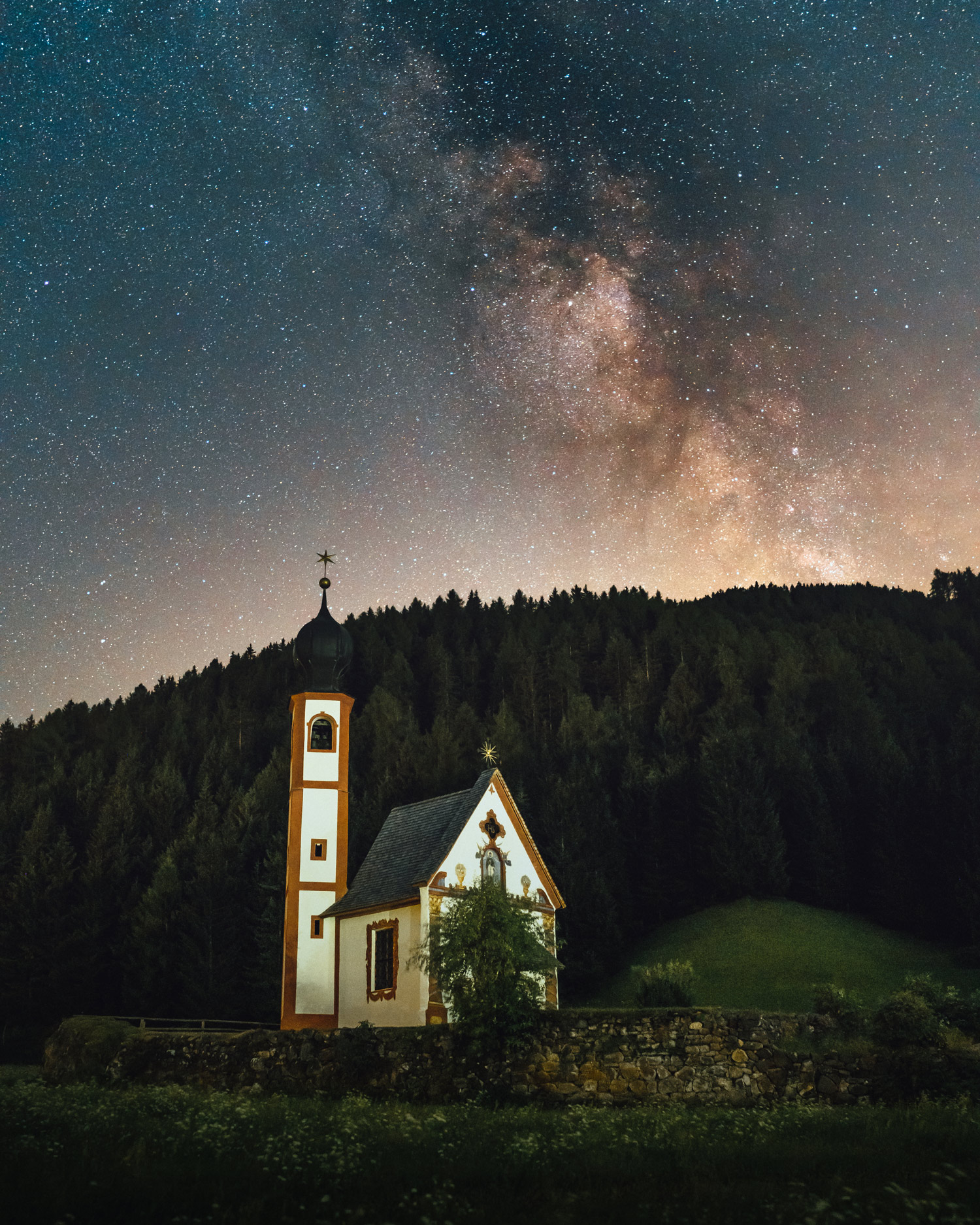 A white church with hills, trees and a star-filled sky in the background, shot bu Jacob Murray with the Sony A7 IV and Sigma 35mm f/1.4 DG DN ART.