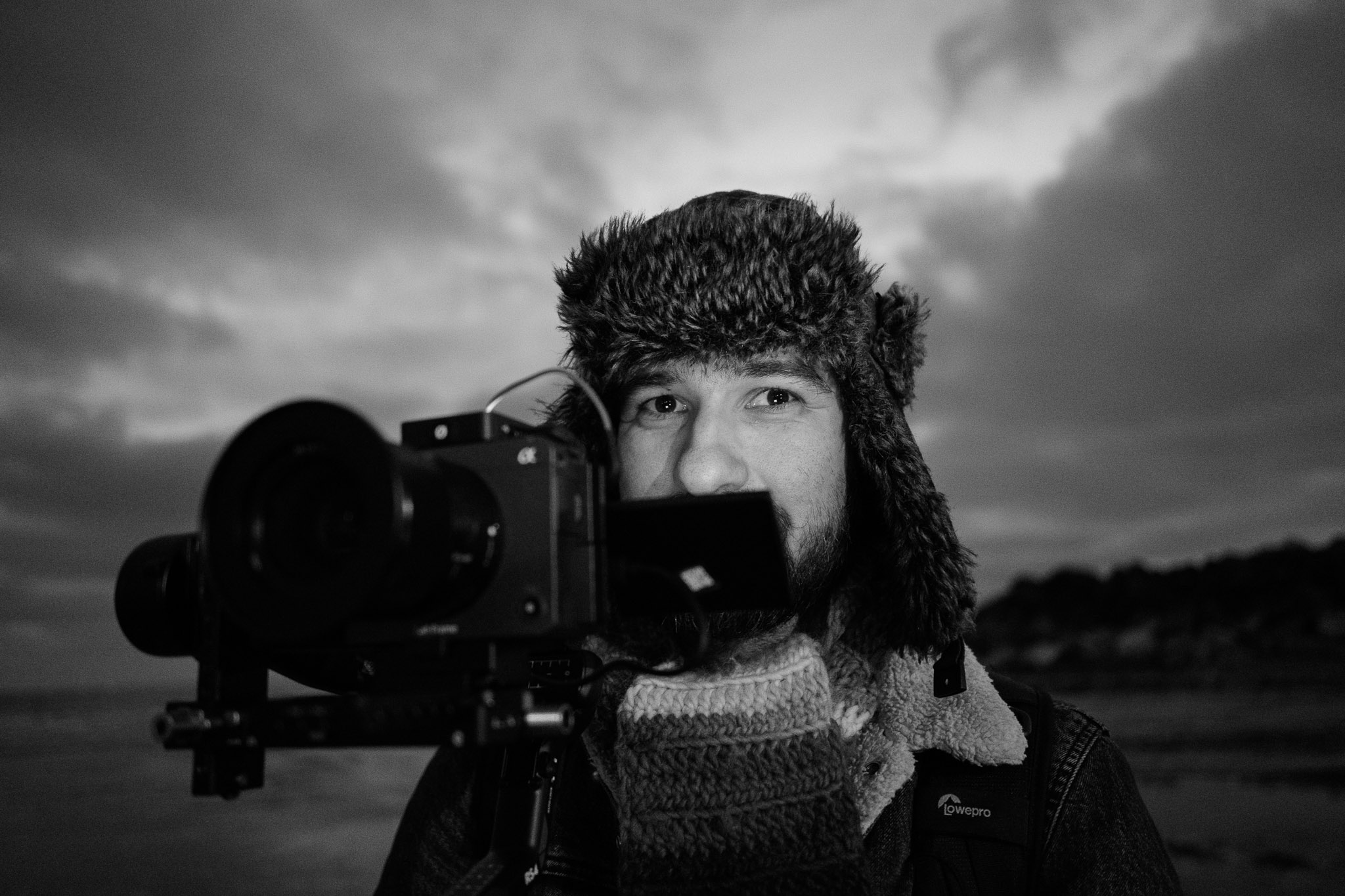 Black and white portrait of a photographer using the Nikon Zf outdoors at dusk, highlighting its low-light performance and eye autofocus accuracy, by Amy Moore.