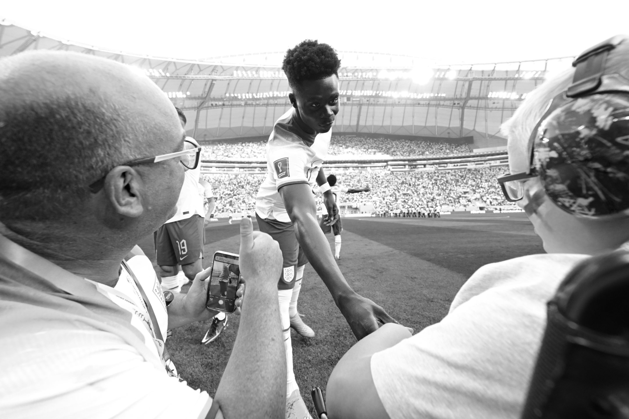 Ein Schwarz-Weiß-Foto von Bukayo Saka, der seine Fans grüßt, nachdem er zwei Tore für England beim 6:2-Sieg gegen den Iran bei der Fußball-Weltmeisterschaft 2022 erzielt hat, aufgenommen mit einer Nikon Z9 von Ryu Voelkel