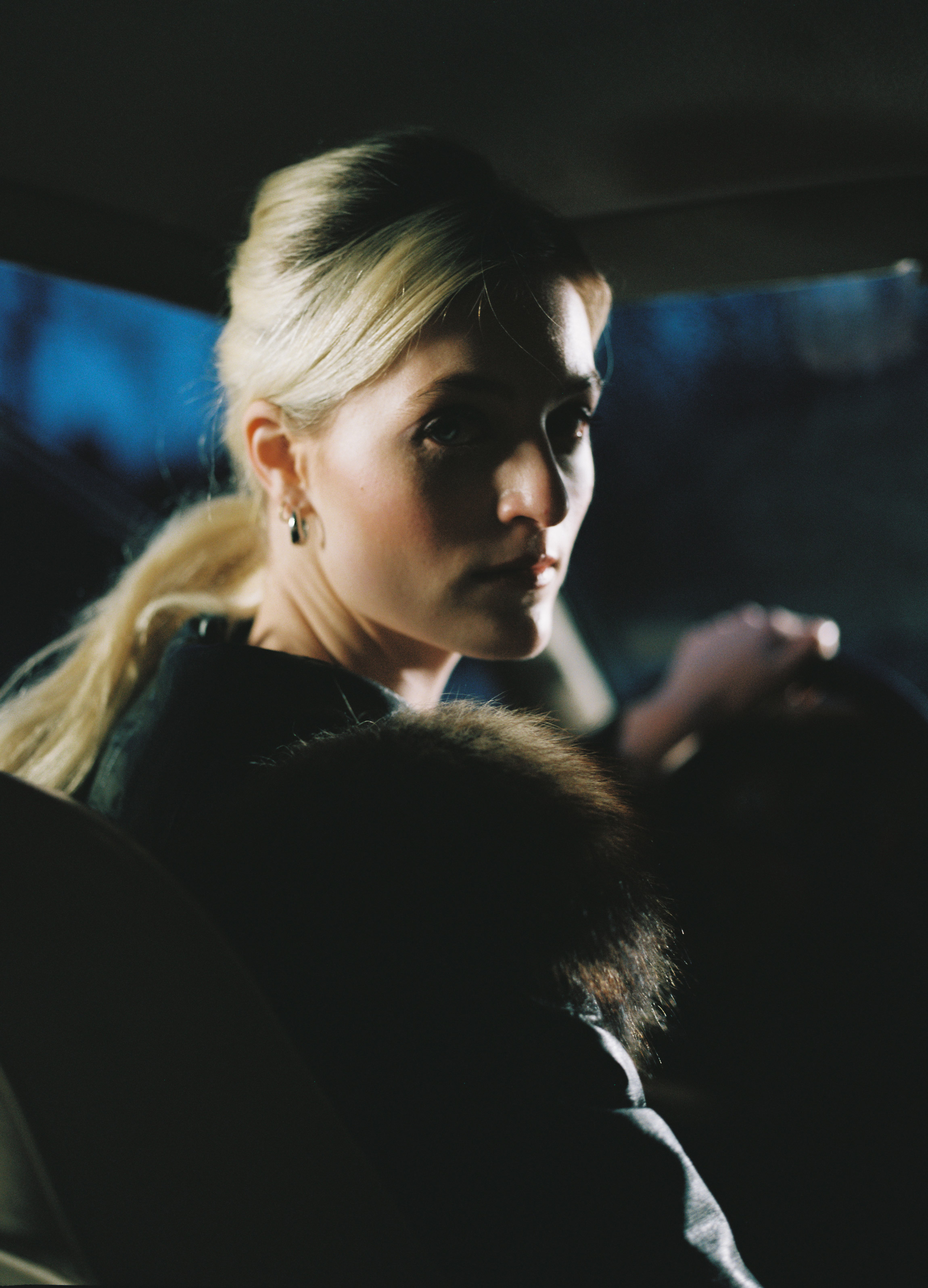 Frau in einem Auto am Steuer, die sich nach hinten rechts umblickt und direkt in die Kamera blickt, aufgenommen von Quyny mit einer Mamiya 645