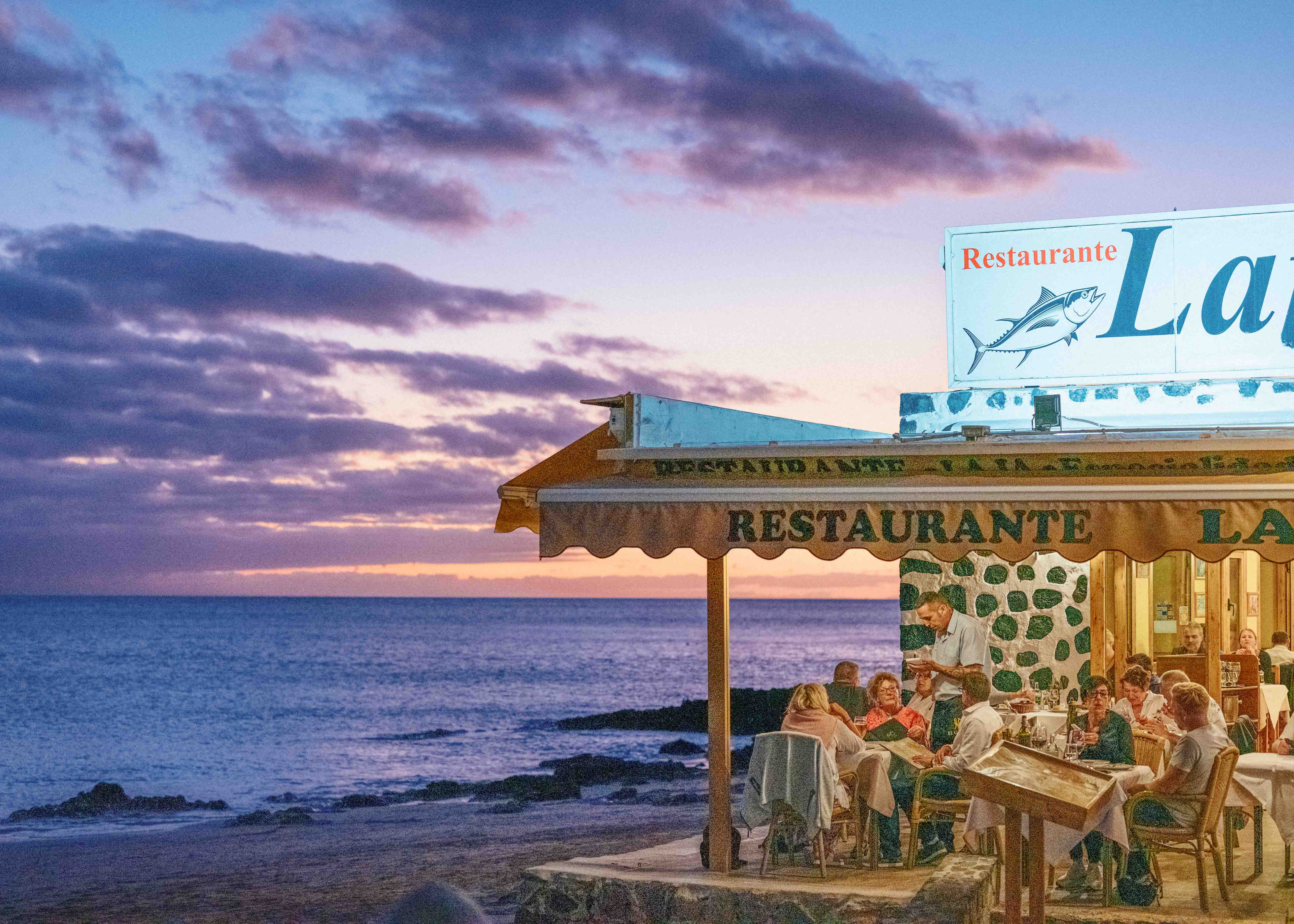 Image of a restaurant on the beachfront at sunset in in Morro Jable, Fuerteventura with the shadows pushed to +100 in Lightroom. Taken on the Fujifilm GFX 50R by Connor Redmond.
