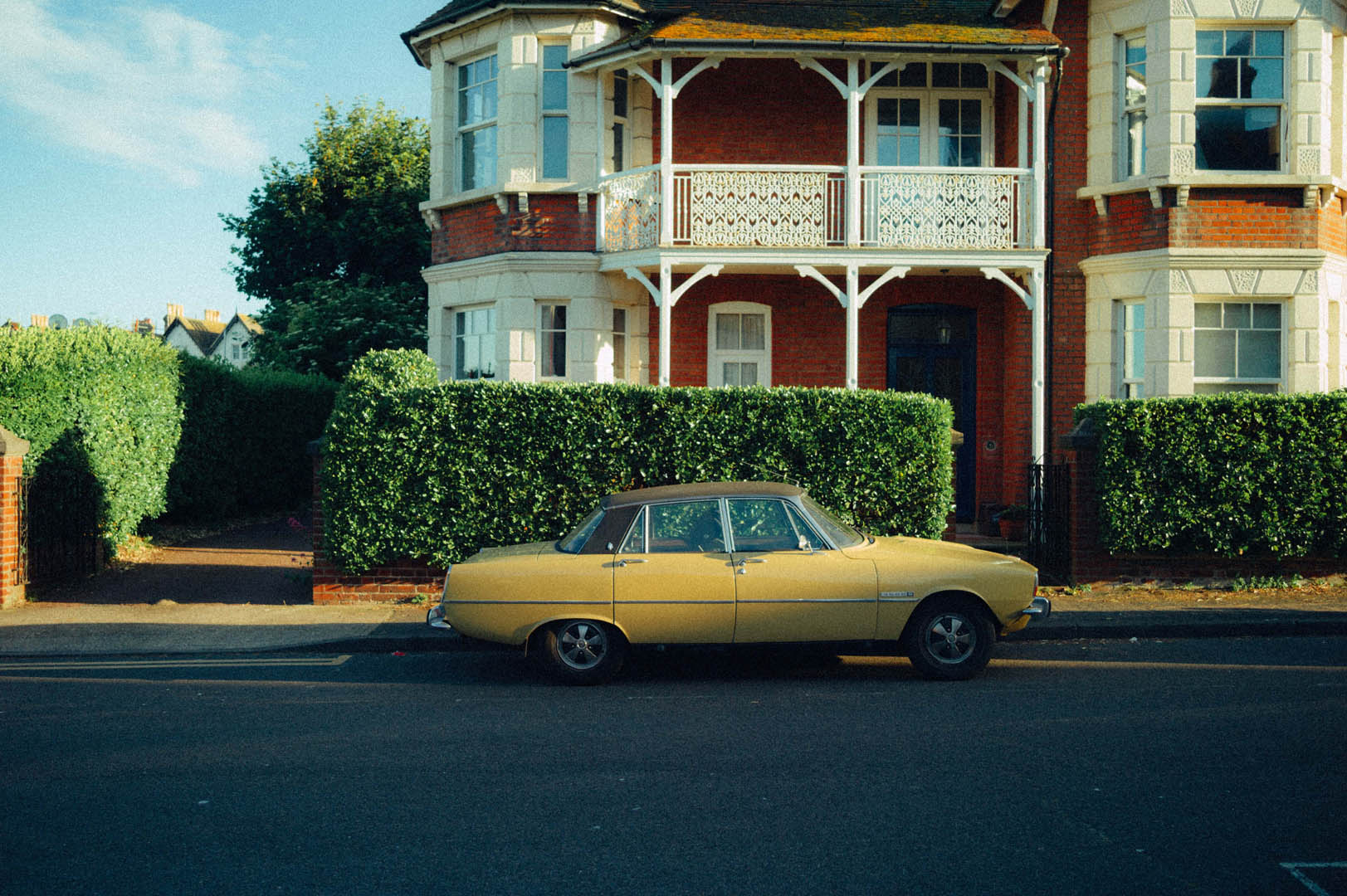 Yellow vintage car parked on the side of a street By Ian Howorth

