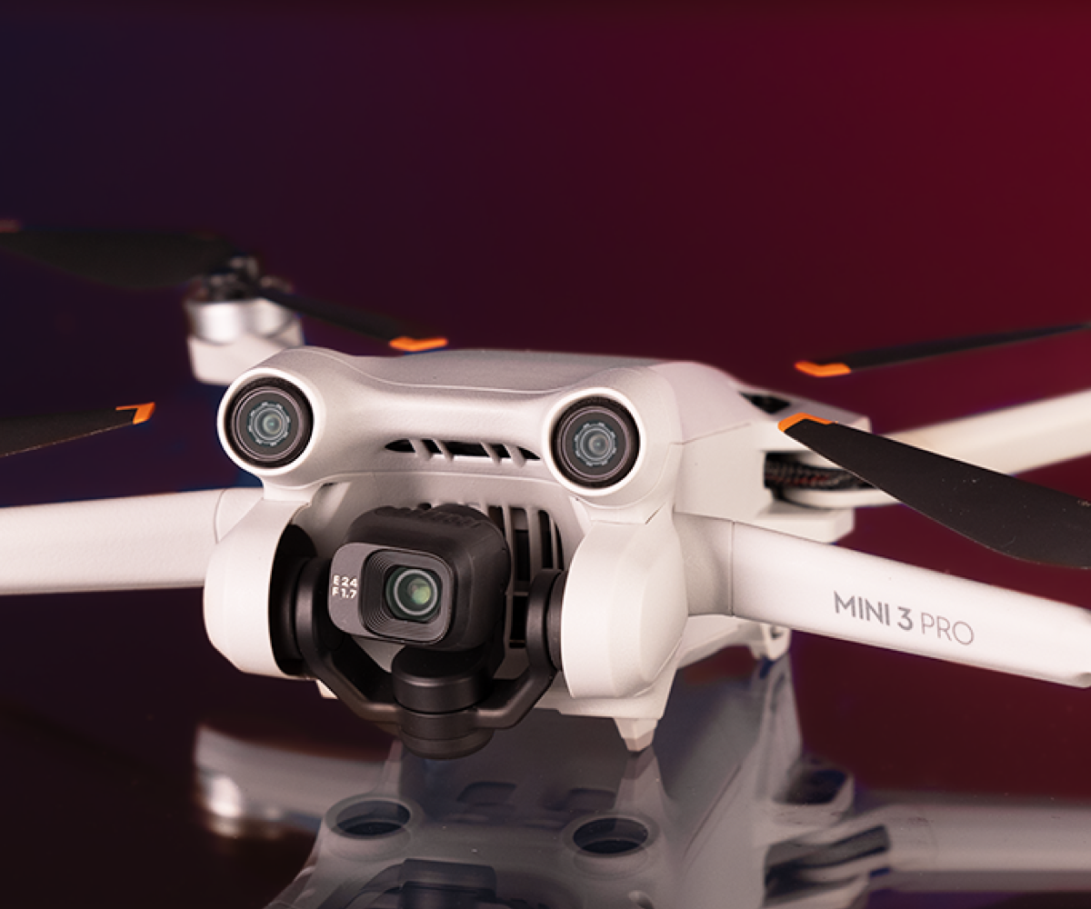 Gebrauchte DJI Mini 3 Pro vor weinrotem Hintergrund.