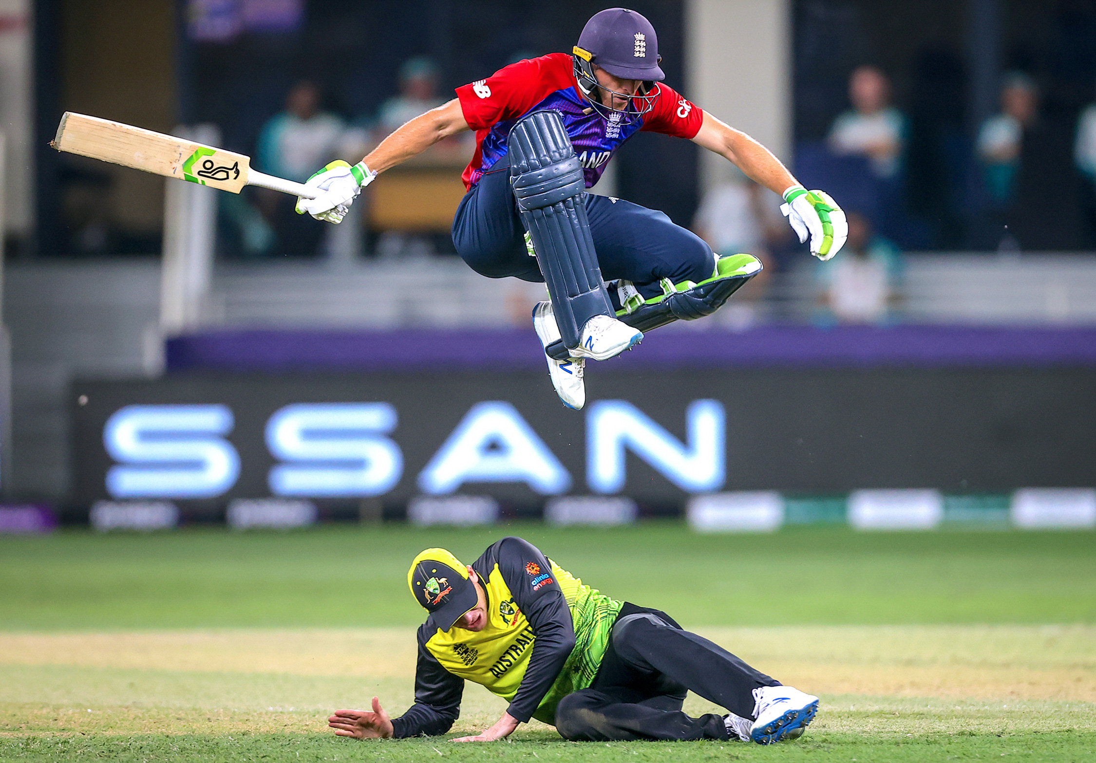 Jos Buttler van Engeland springt over Steve Smith van Australië tijdens de ICC Men's T20 World Cup cricketwedstrijd tussen Engeland en Australië in het Dubai International Cricket Stadium in Dubai, zaterdag 30 oktober 2021.