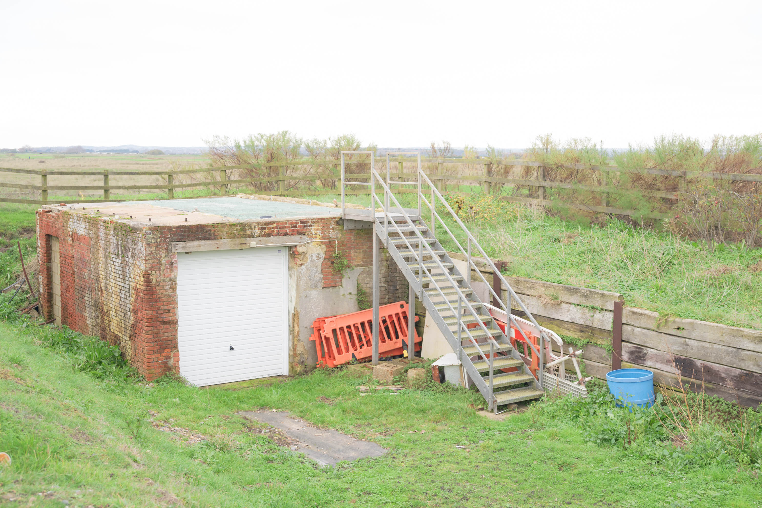 Small brick utility building with exterior metal stairs in a rural landscape, photographed with the Nikon Zf by Connor Redmond.