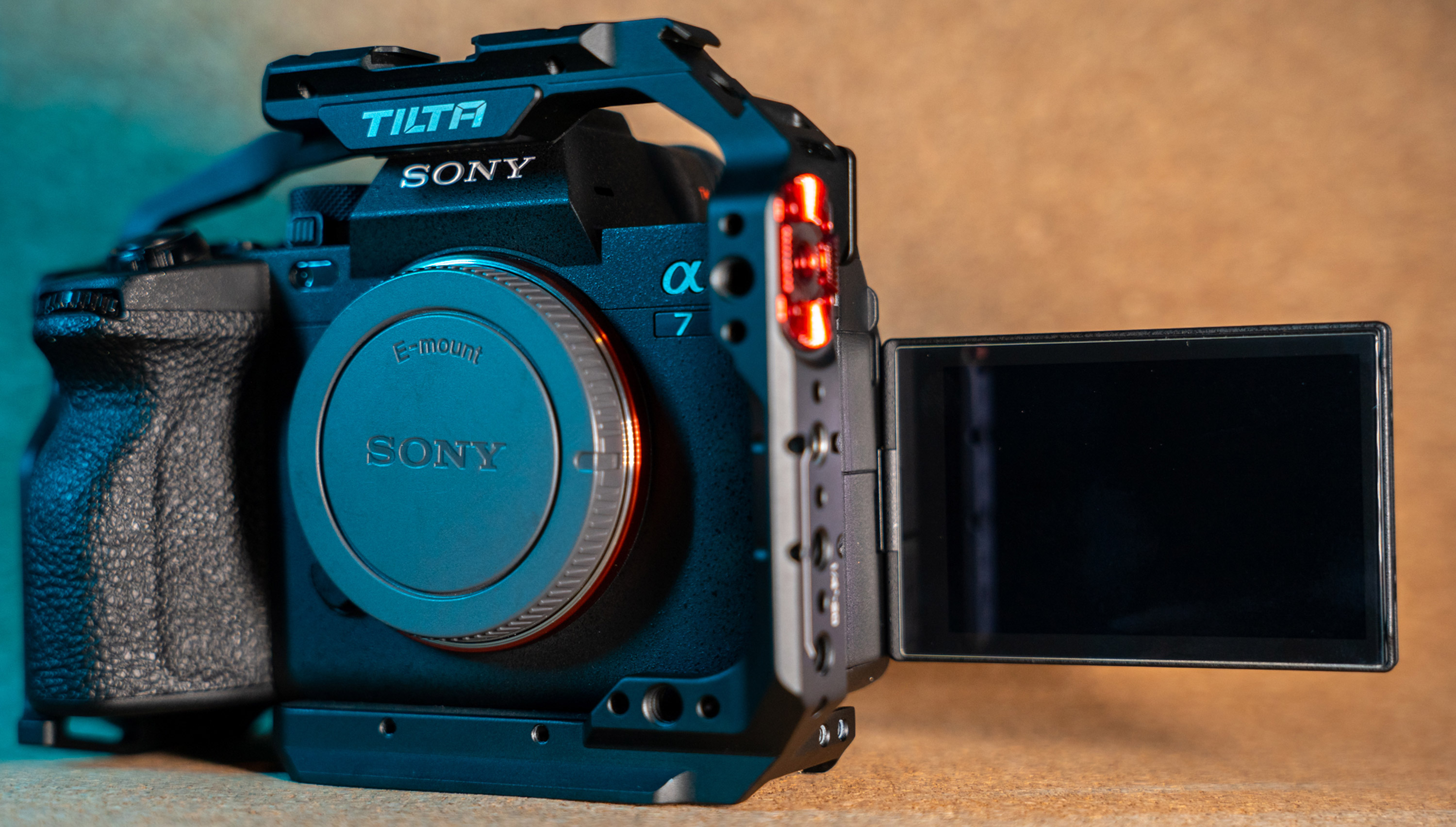 Sony A7 IV avec la cage de caméra Tilta et l'écran pivotant, devant un fond orangé