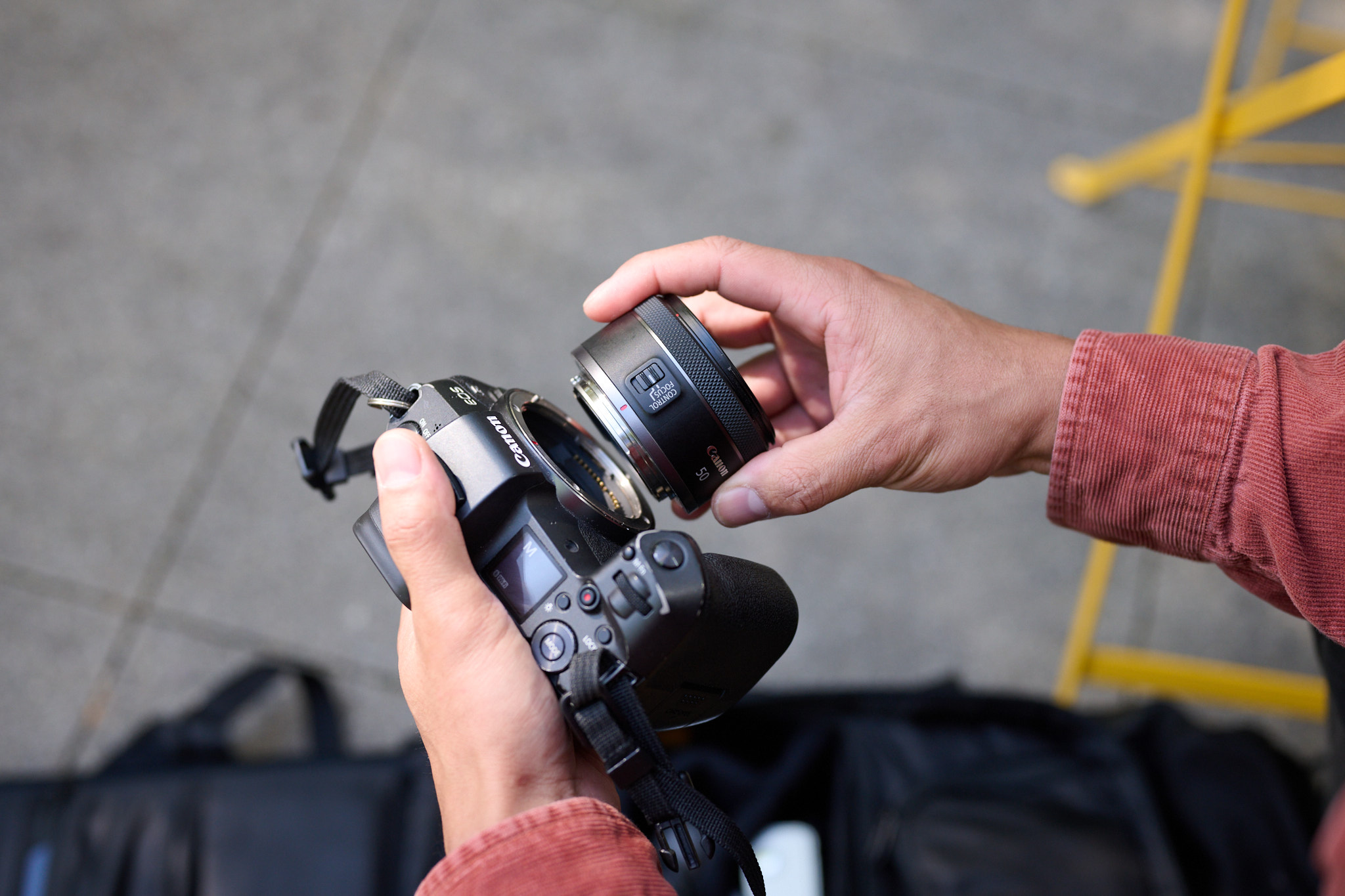 A pair of hands mounting a lens to a Canon mirrorless camera