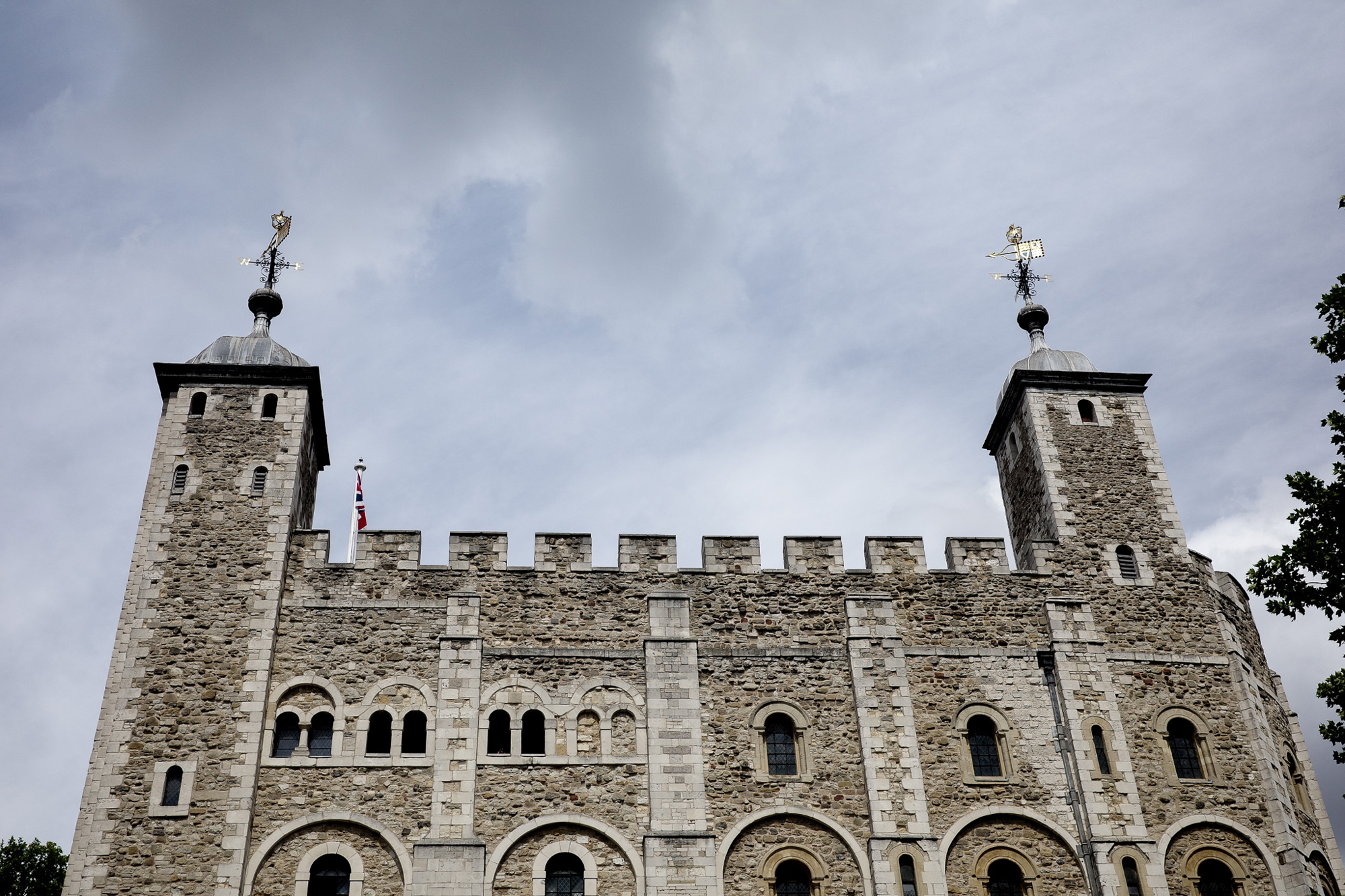 Een beeld vanuit een lage hoek van de Tower of London tegen een grijze wolkenlucht