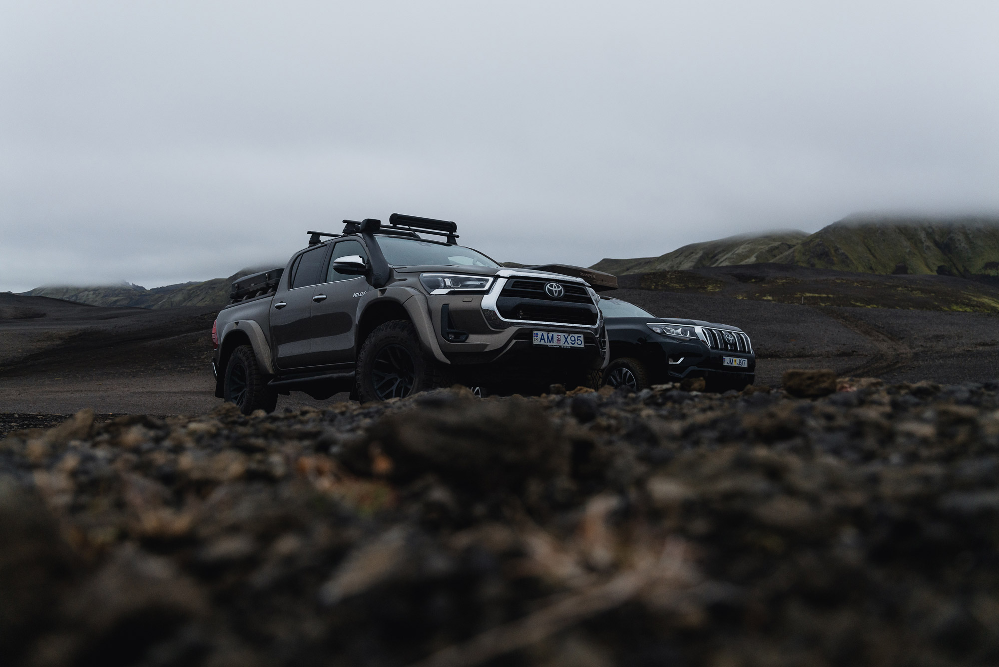 Zwei SUV-Geländewagen, umgeben von Nebel und Bergen auf Island, im Vordergrund Trümmer und im Hintergrund von Wolken verdeckte Berge, aufgenommen von Paul Watson mit einer Panasonic S1R