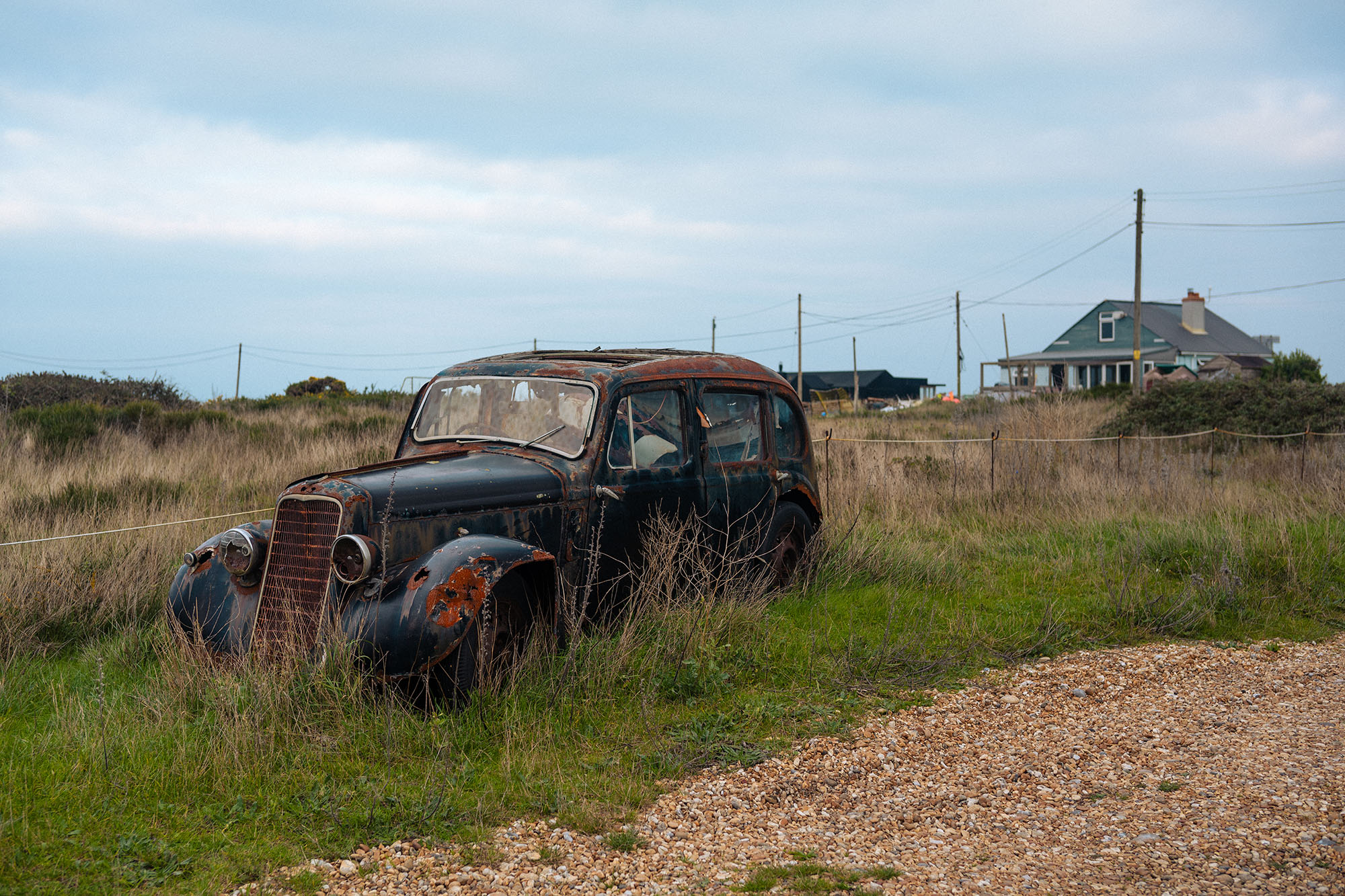 Un coche vintage y oxidado en una playa de guijarros