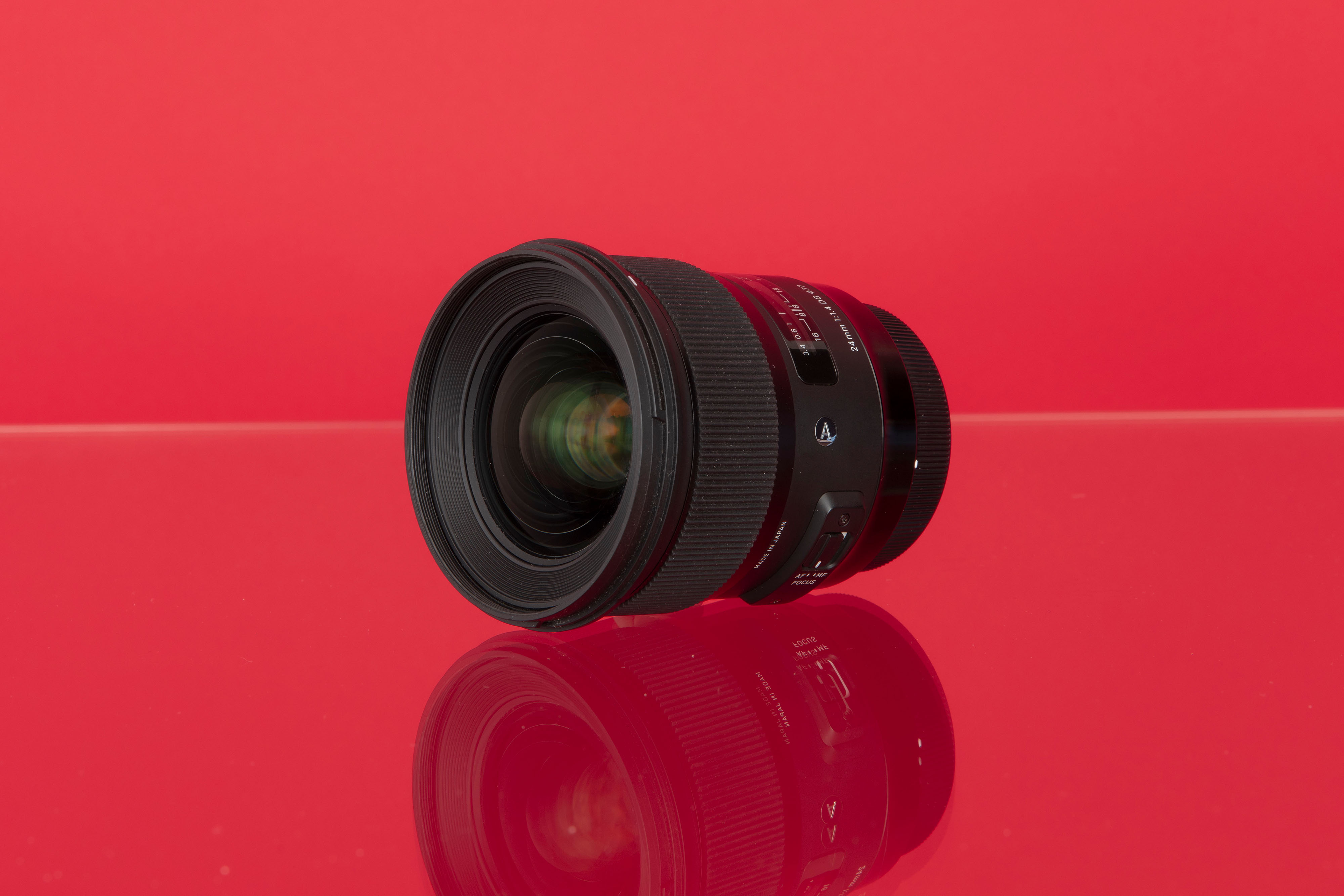 Een Sigma 24mm f/1.4 DG HSM ART prime lens tegen een rode achtergrond