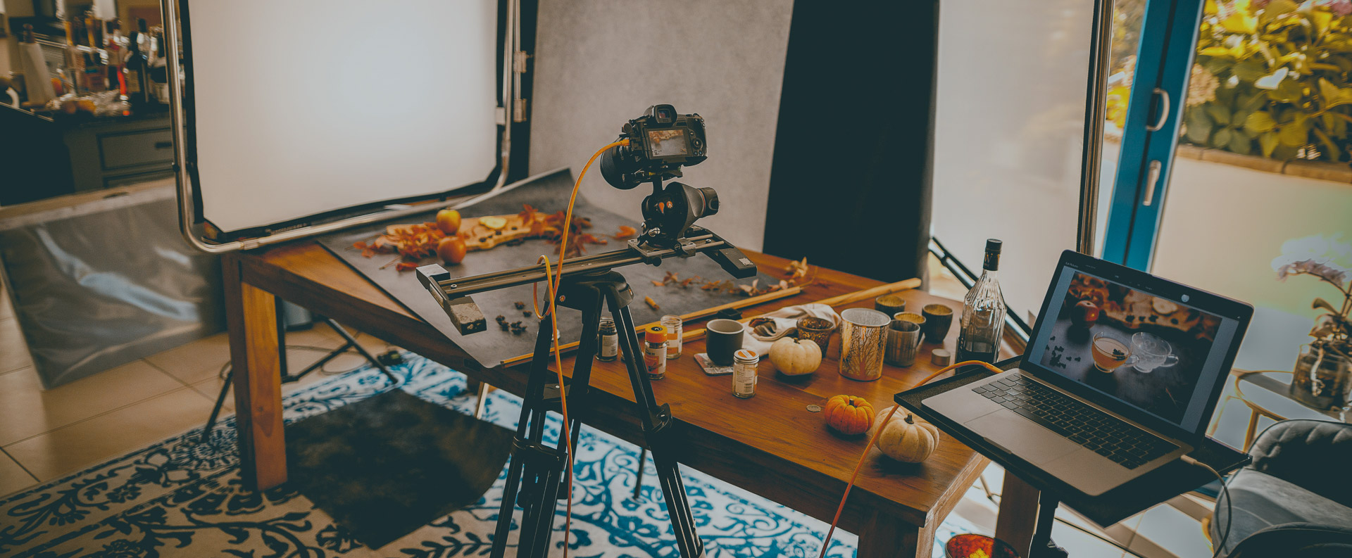 A food photography studio with a tripod and camera tethered to a laptop on a table