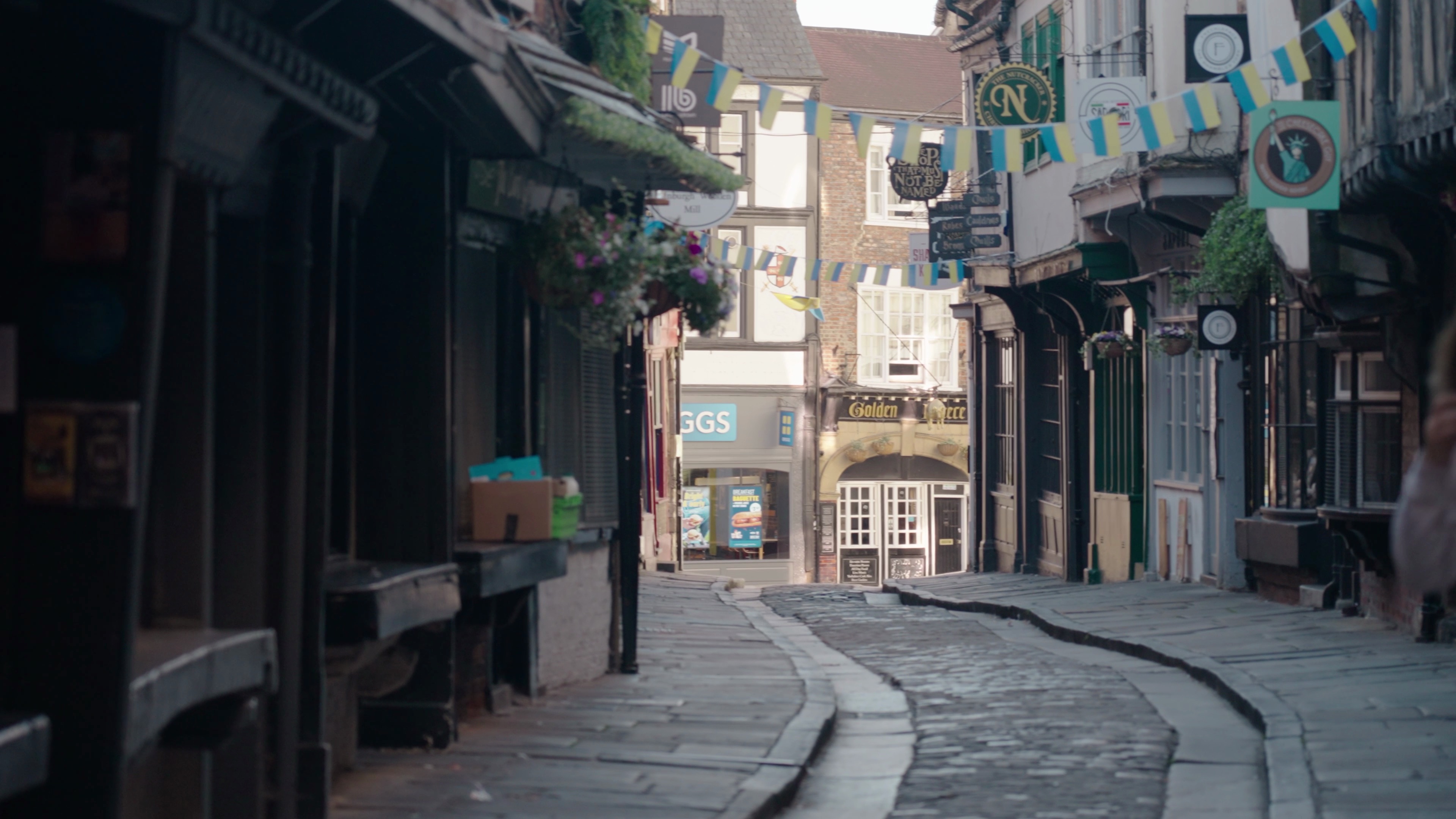 Photo du quartier des Shambles à York, avec la moitié d'une enseigne Gregg's au bout de la rue.
