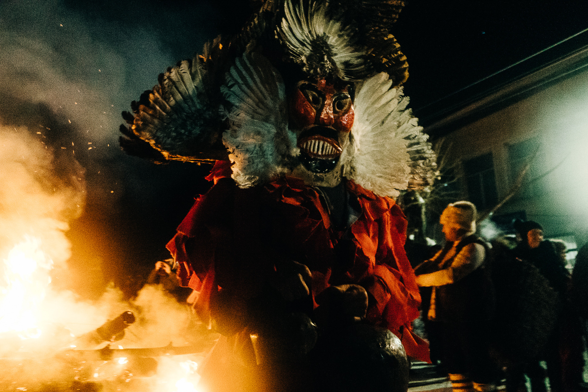 Uma figura folclórica mascarada rodeada de escuridão e chamas, fotografada na Bulgária por Roman K.