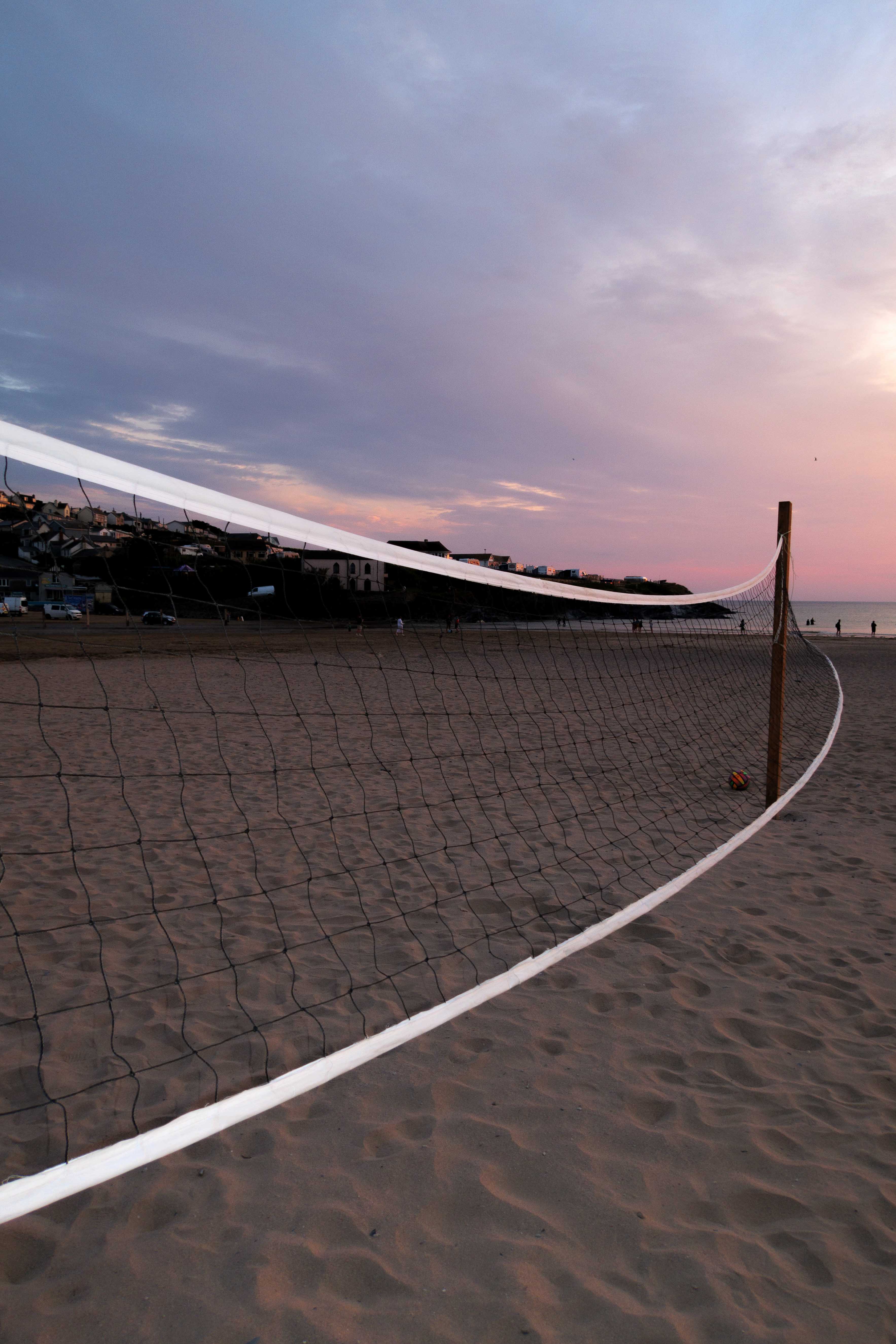 Volleyball net on the beach illuminated by flash with sunset in the background

