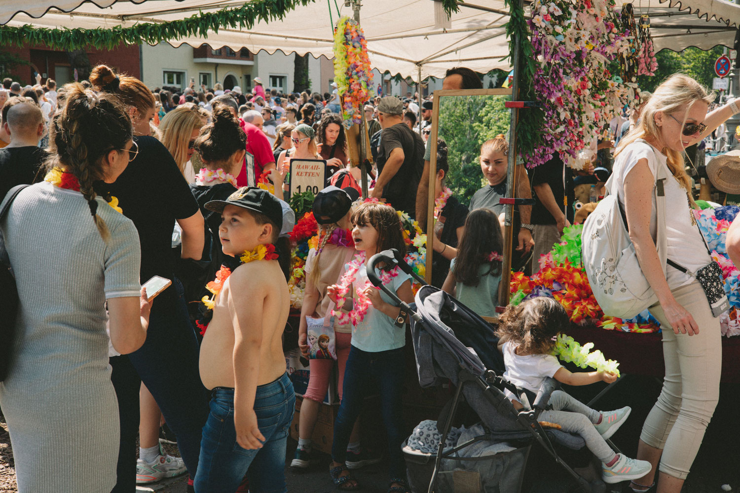 Crowd in front of a stall selling colourful flower necklaces, shot by Stefanie Schmid Rincon with the Canon EOS R6.