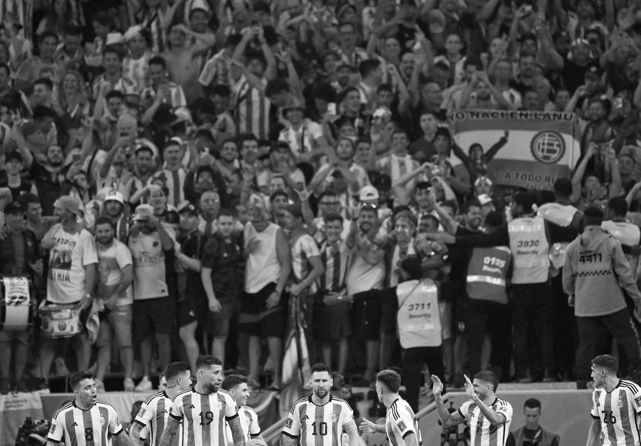 Photo en noir et blanc de Lionel Messi et de l'équipe d'Argentine, avec leurs supporters en arrière-plan, célébrant leur victoire 2-1 sur l'Australie en huitième de finale de la Coupe du monde 2022, prise par Ryu Voelkel avec un Nikon Z9