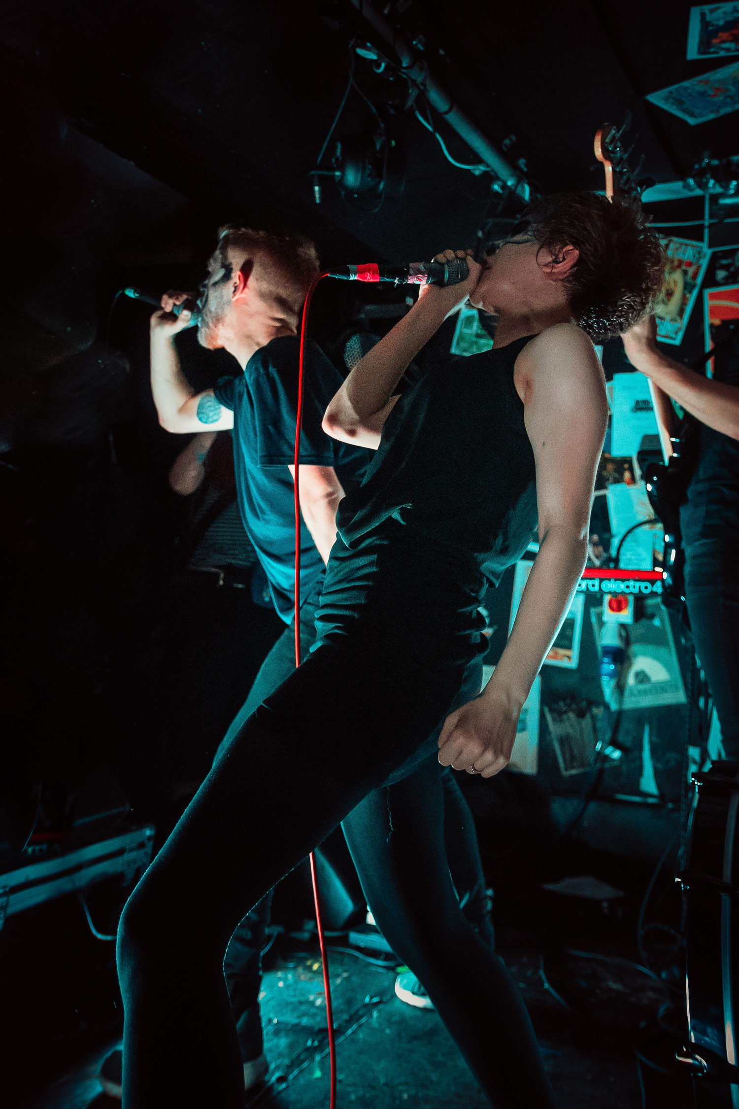 Two singers of a band dressed in black singing on a dark stage, shot by Chloe Imbach with a Canon EOS 80D
