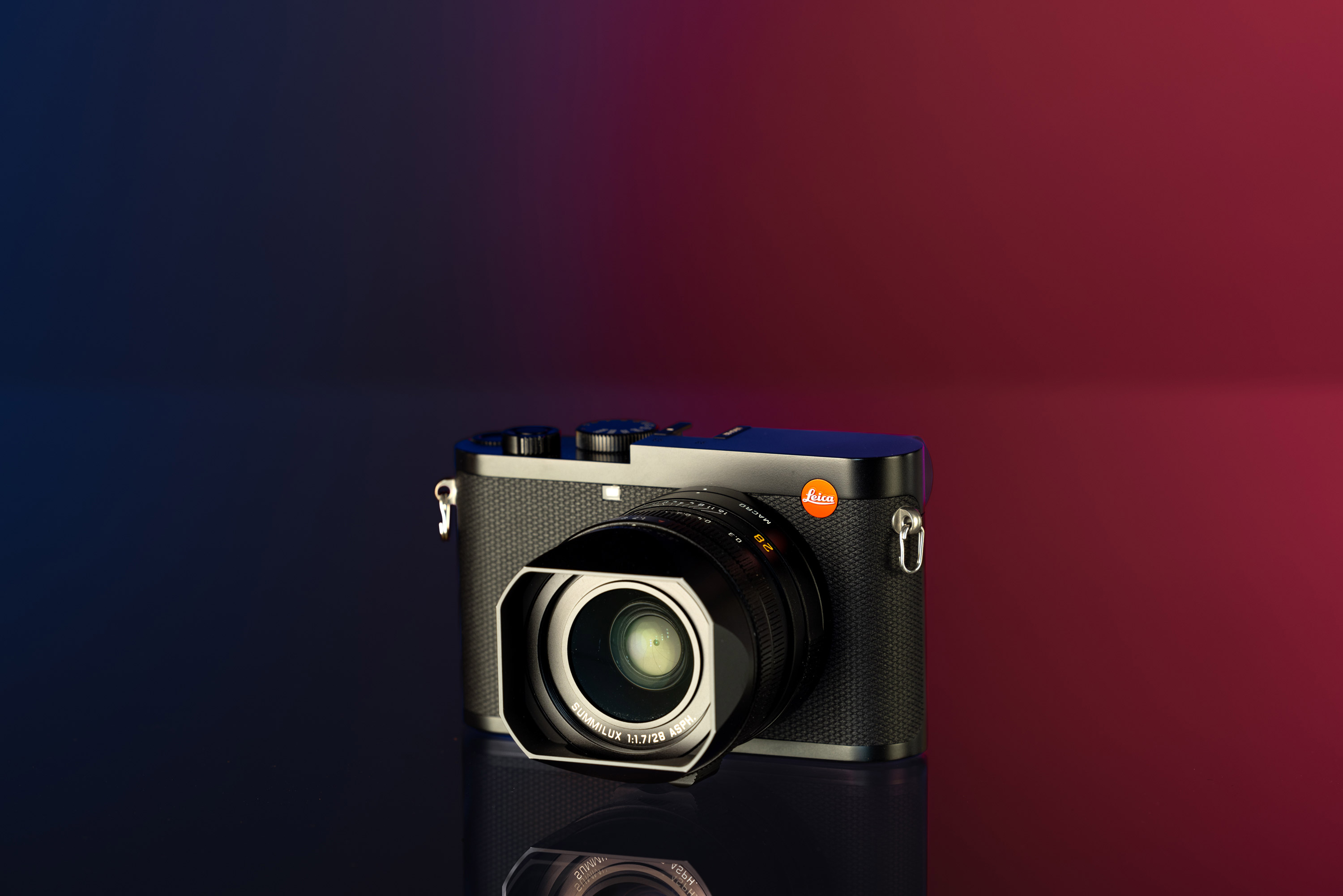 Gebrauchte Leica Q2 vor einem rot-blauen Hintergrund.