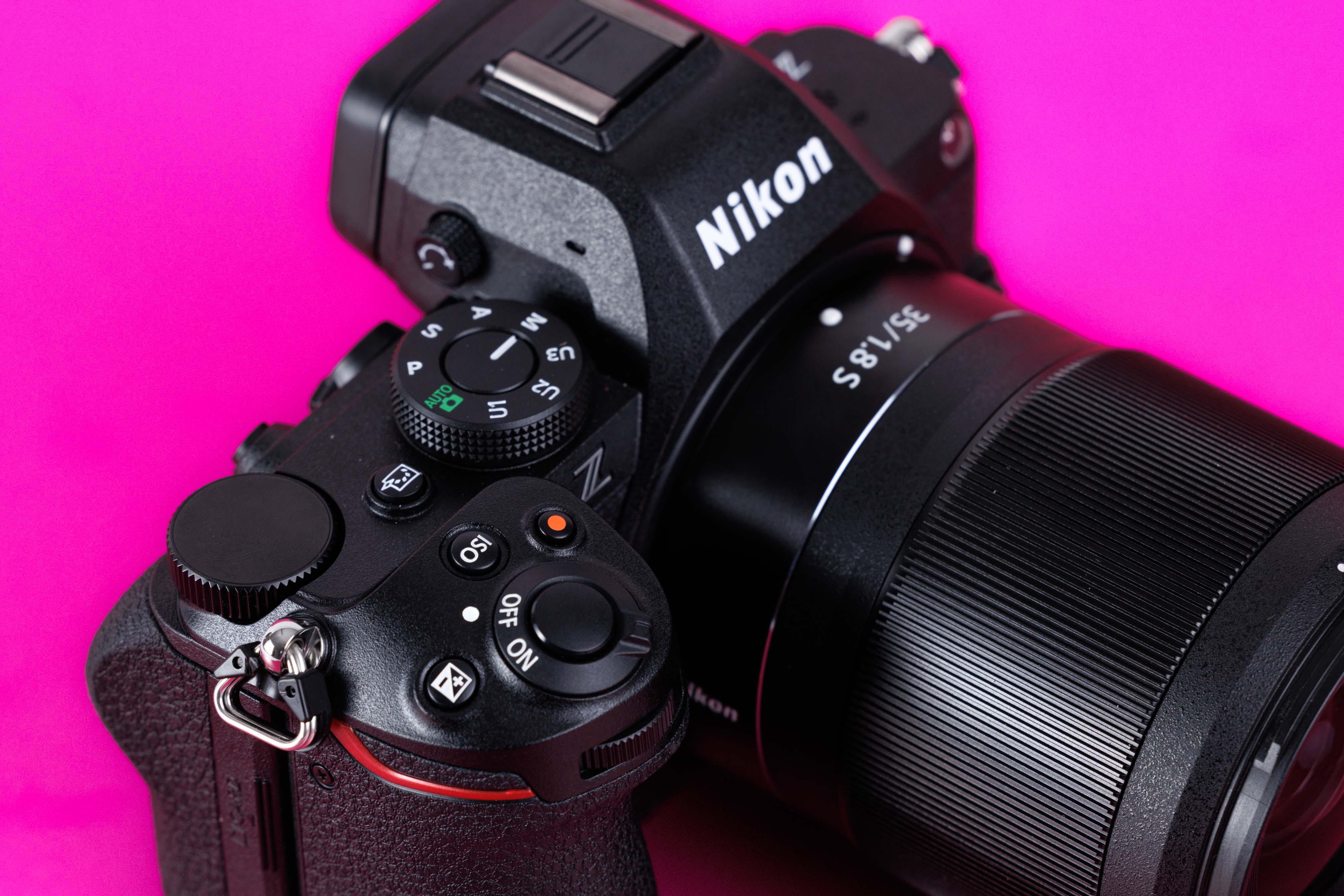 Detailaufnahme der oberen Bedienelemente einer gebrauchten Nikon Z5 II vor leuchtend pinkem Studiohintergrund