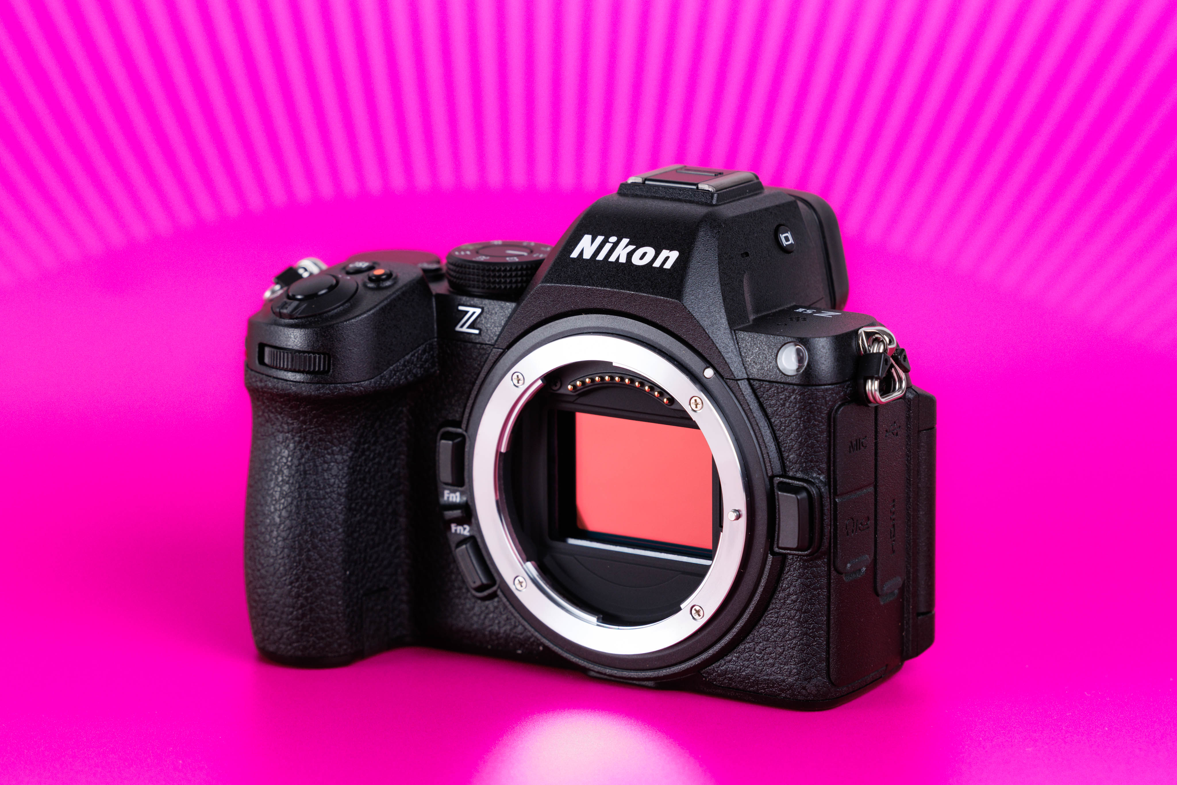 Studioaufnahme einer gebrauchten Nikon Z5 II mit freiliegendem Sensor vor leuchtend pinkem Hintergrund